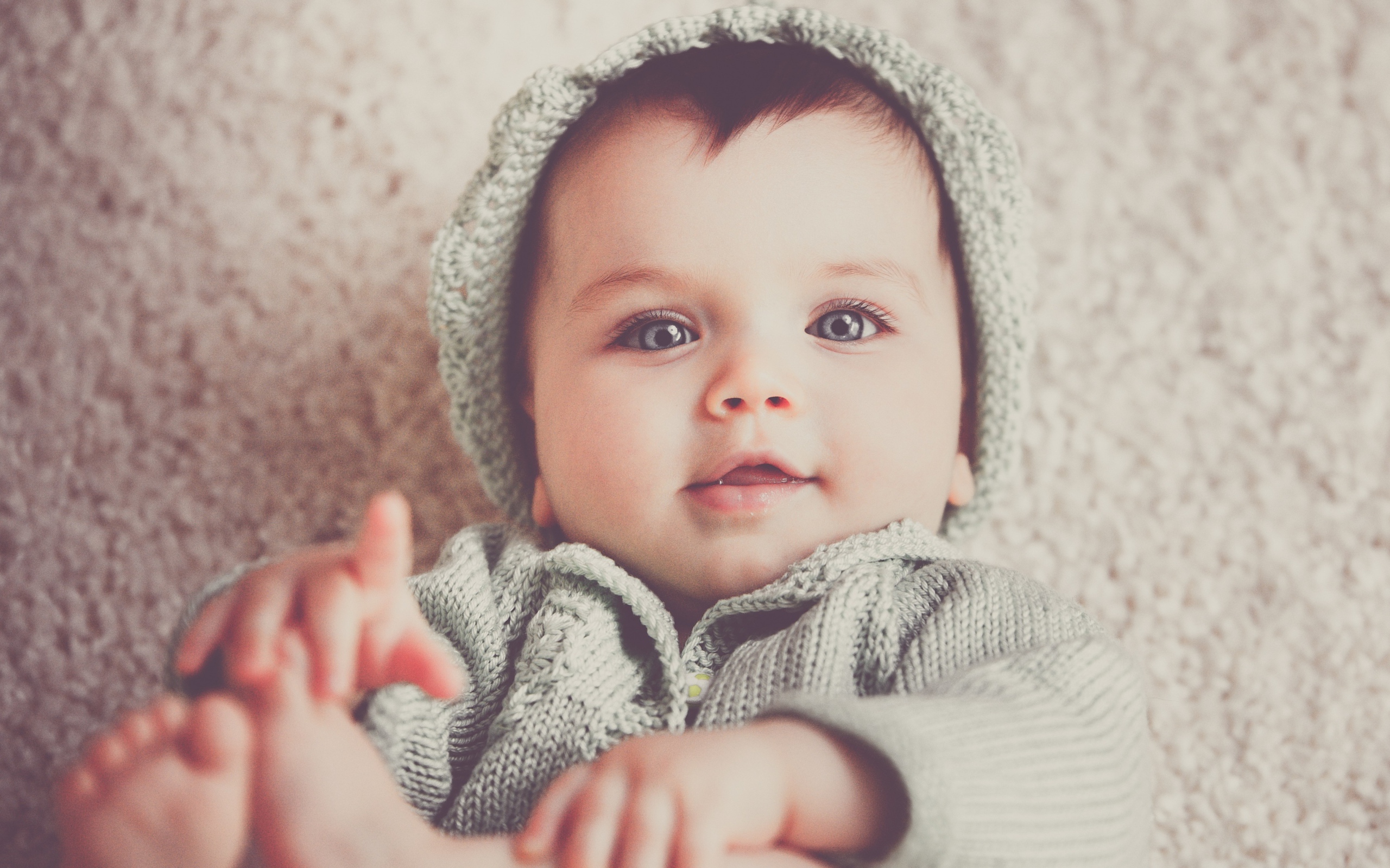 Маленький милый голубоглазый малыш в вязаном костюме