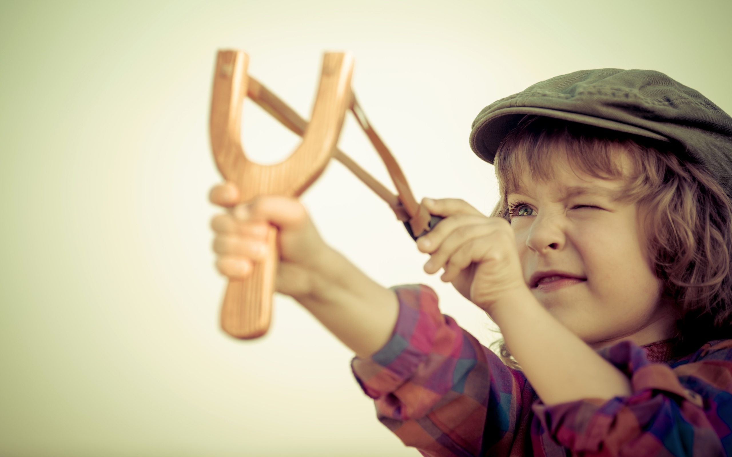 Маленький мальчик в кепке целится с рогатки