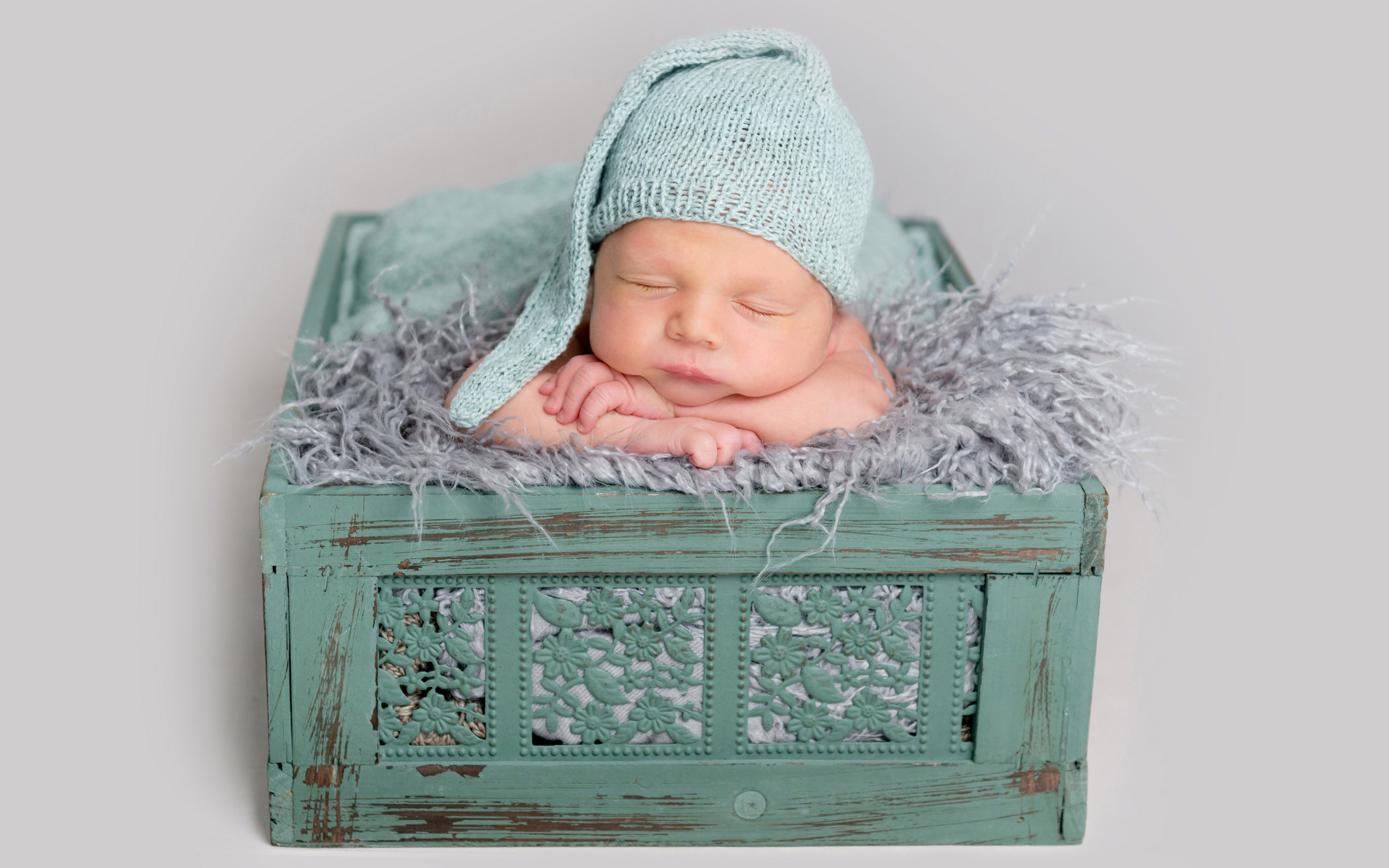 Спящий ребенок в зеленом ящике на сером фоне