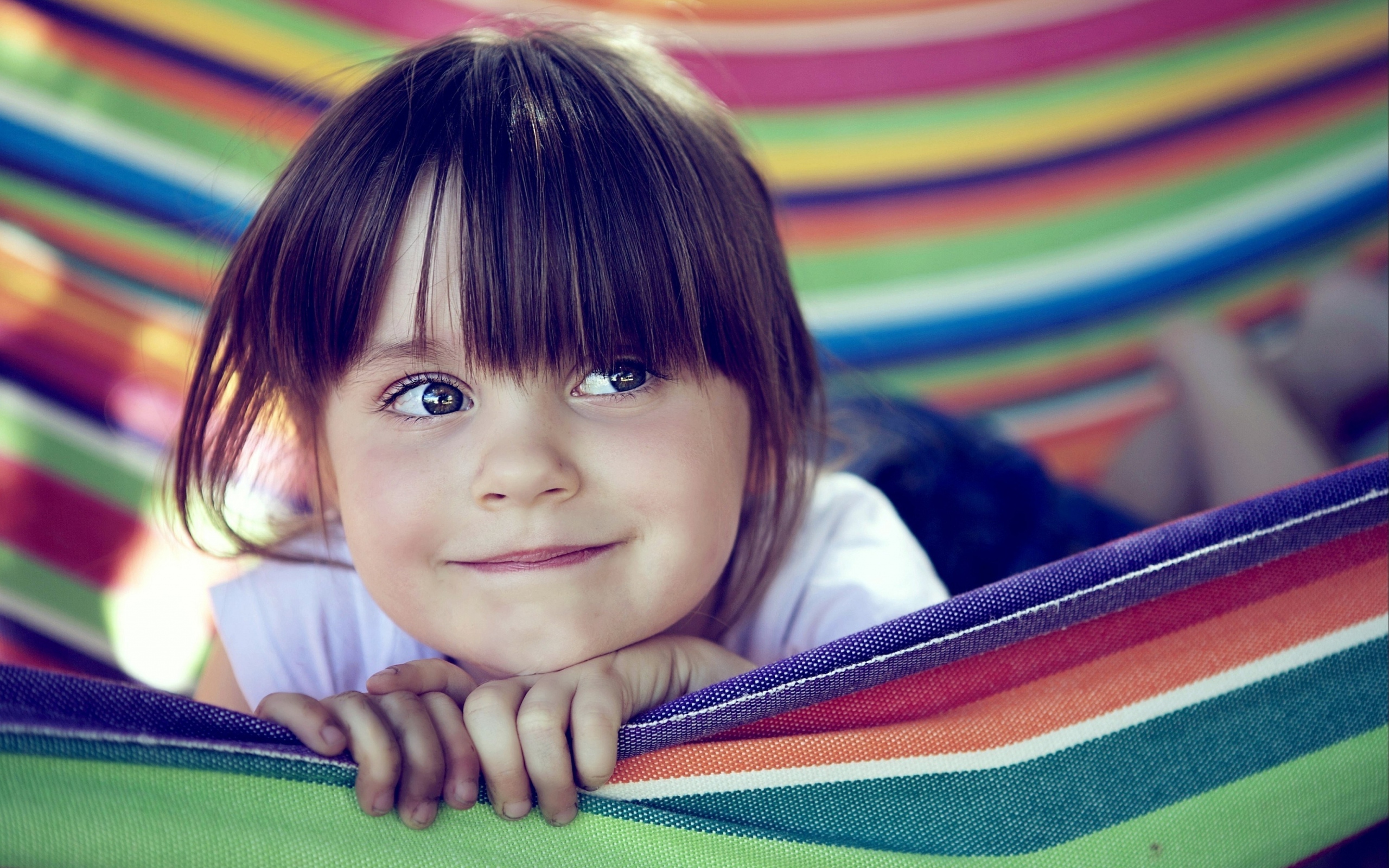 Маленькая кареглазая девочка лежит в гамаке