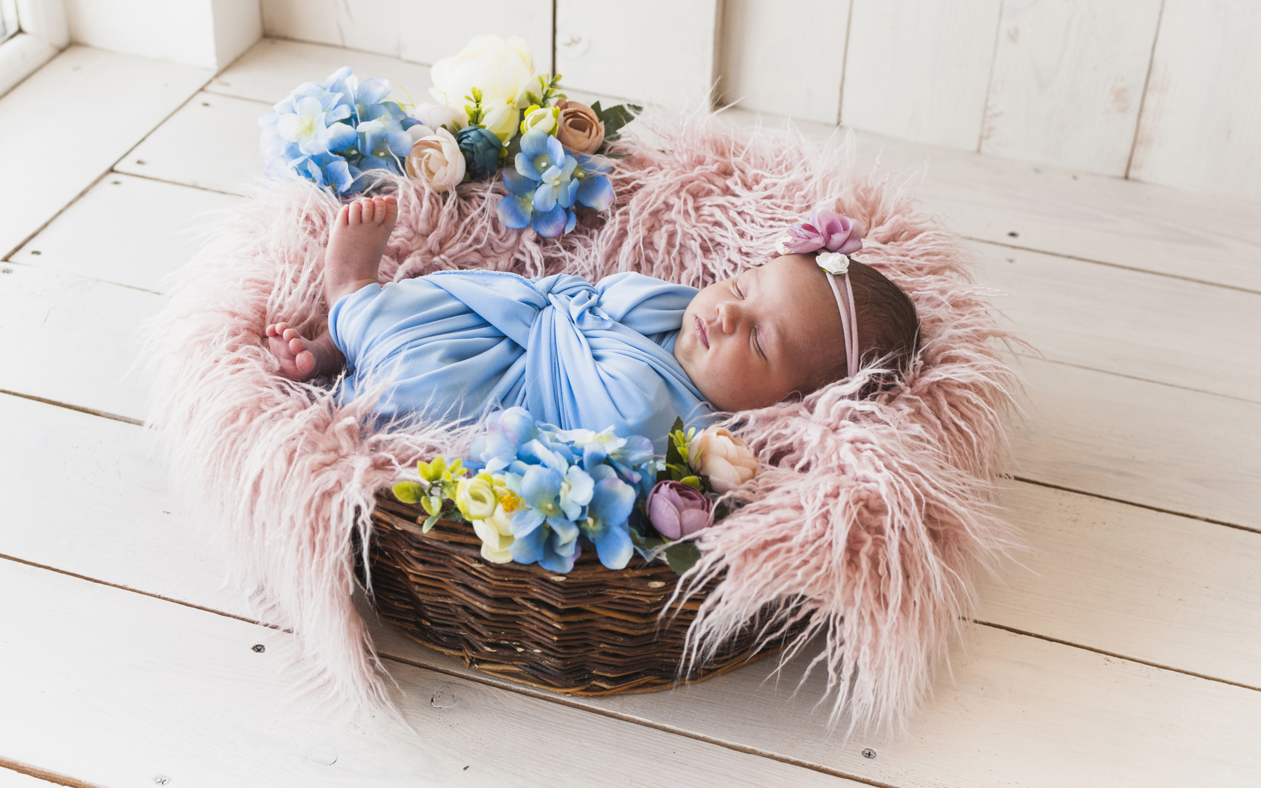 Маленький грудной ребенок спит в плетеной корзине 