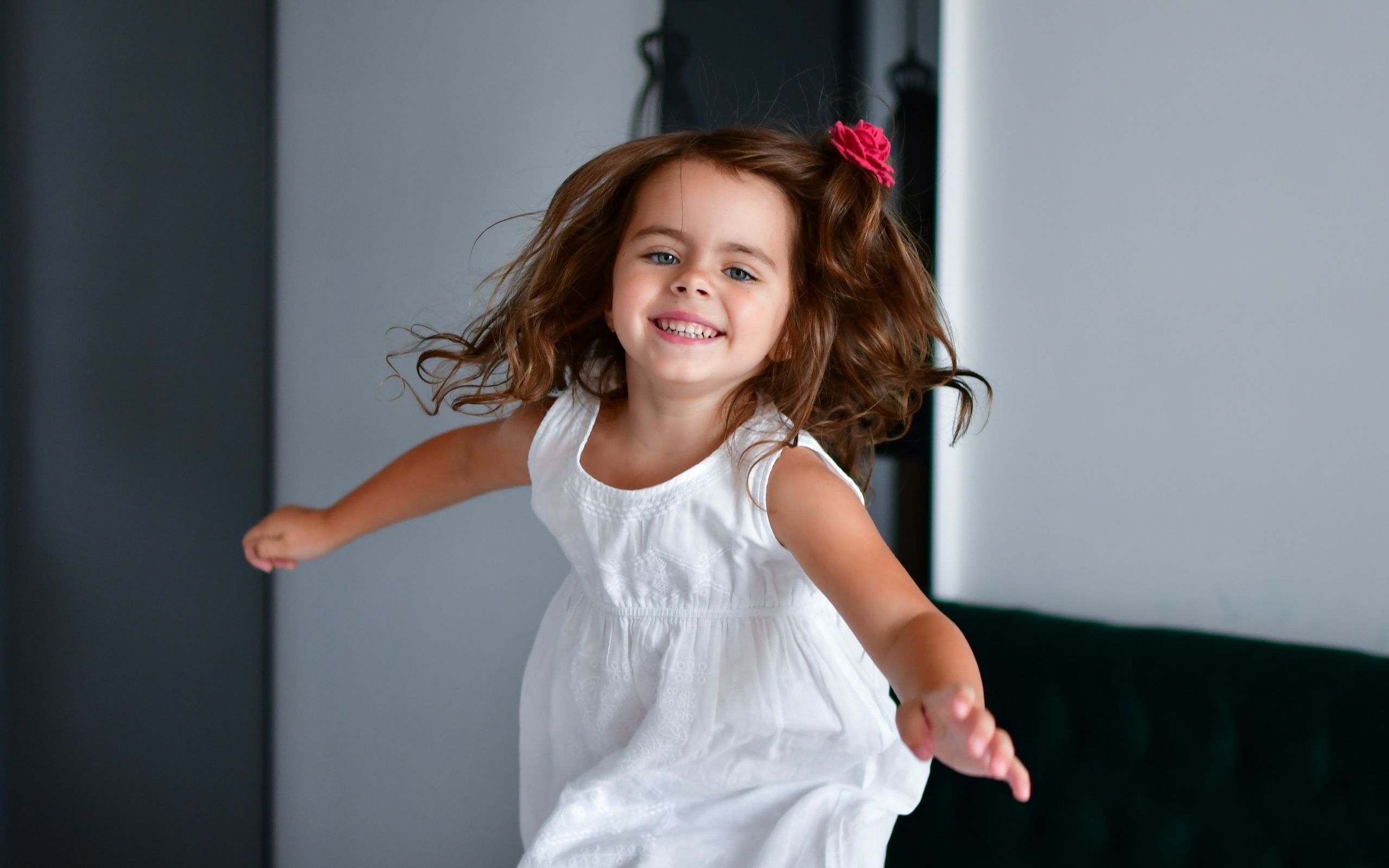 Маленькая веселая девочка в белом платье