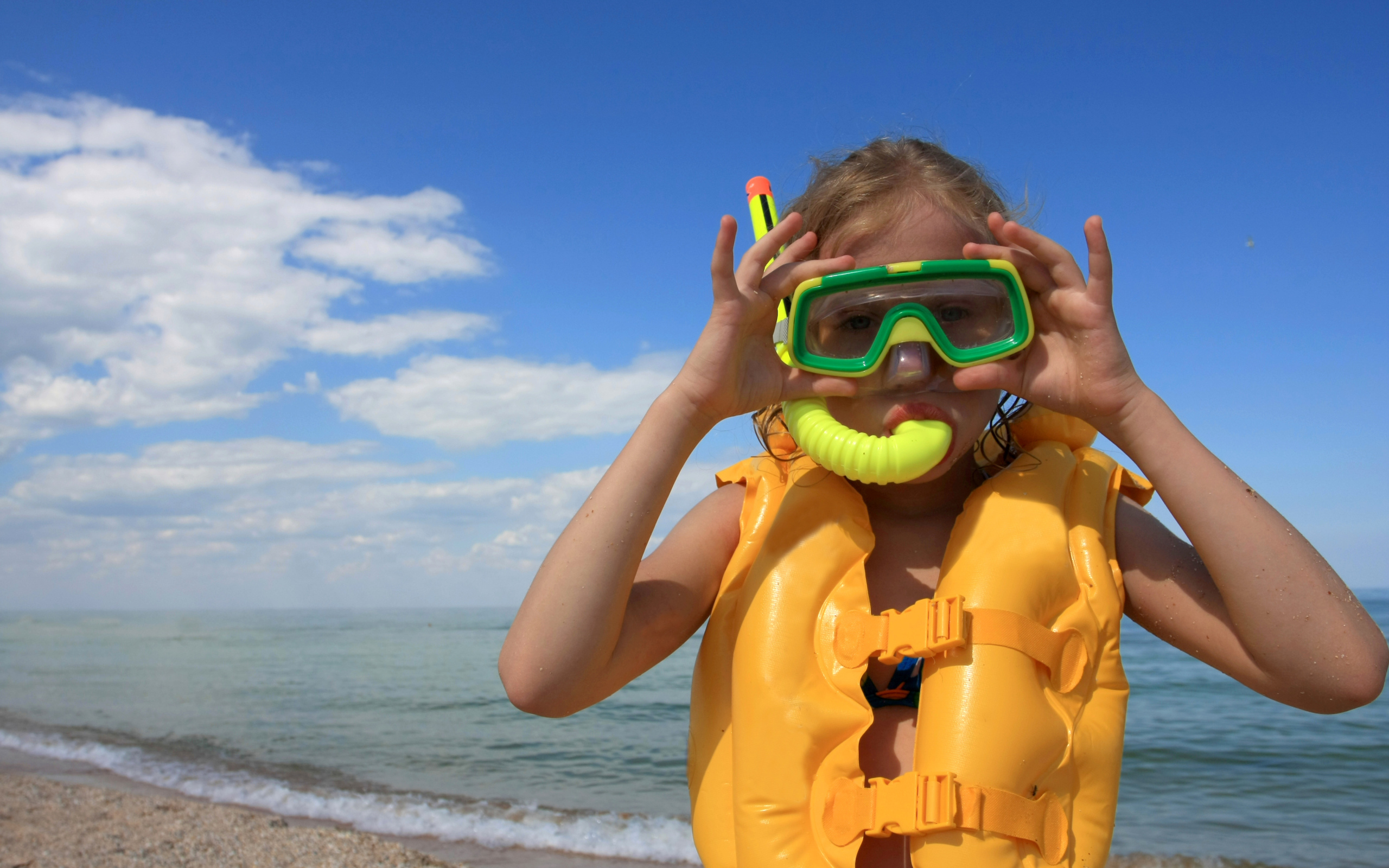 Маленькая девочка в маске и спасательном жилете на море