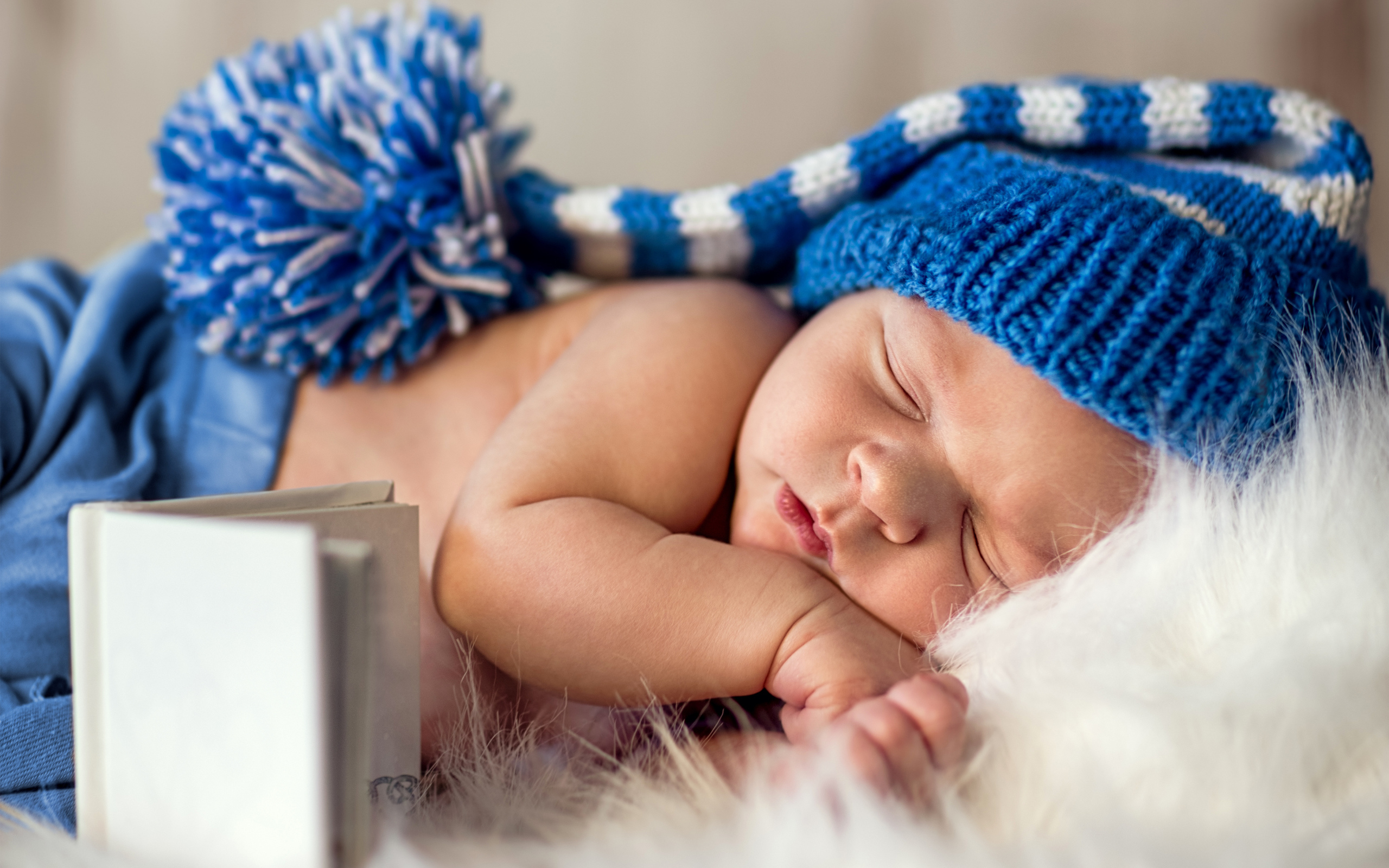 Маленький спящий грудной ребенок в синей вязанной шапке 