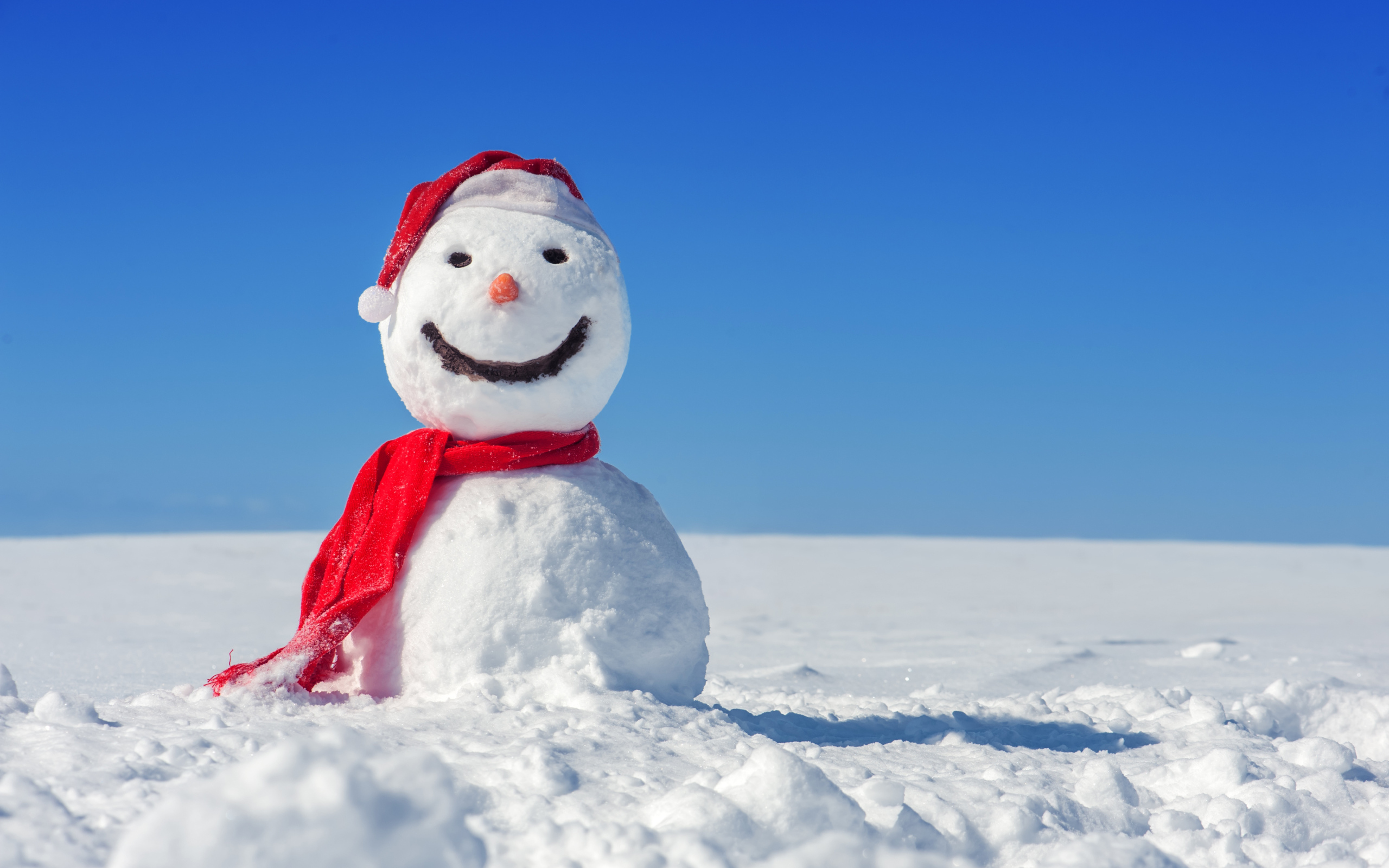 Веселый снеговик в красной шапке на белом снегу