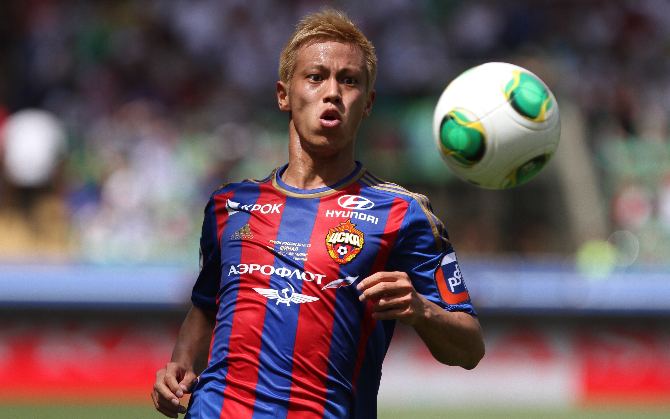 Японский футболист Кэйсукэ Хонда отбивает мяч на поле