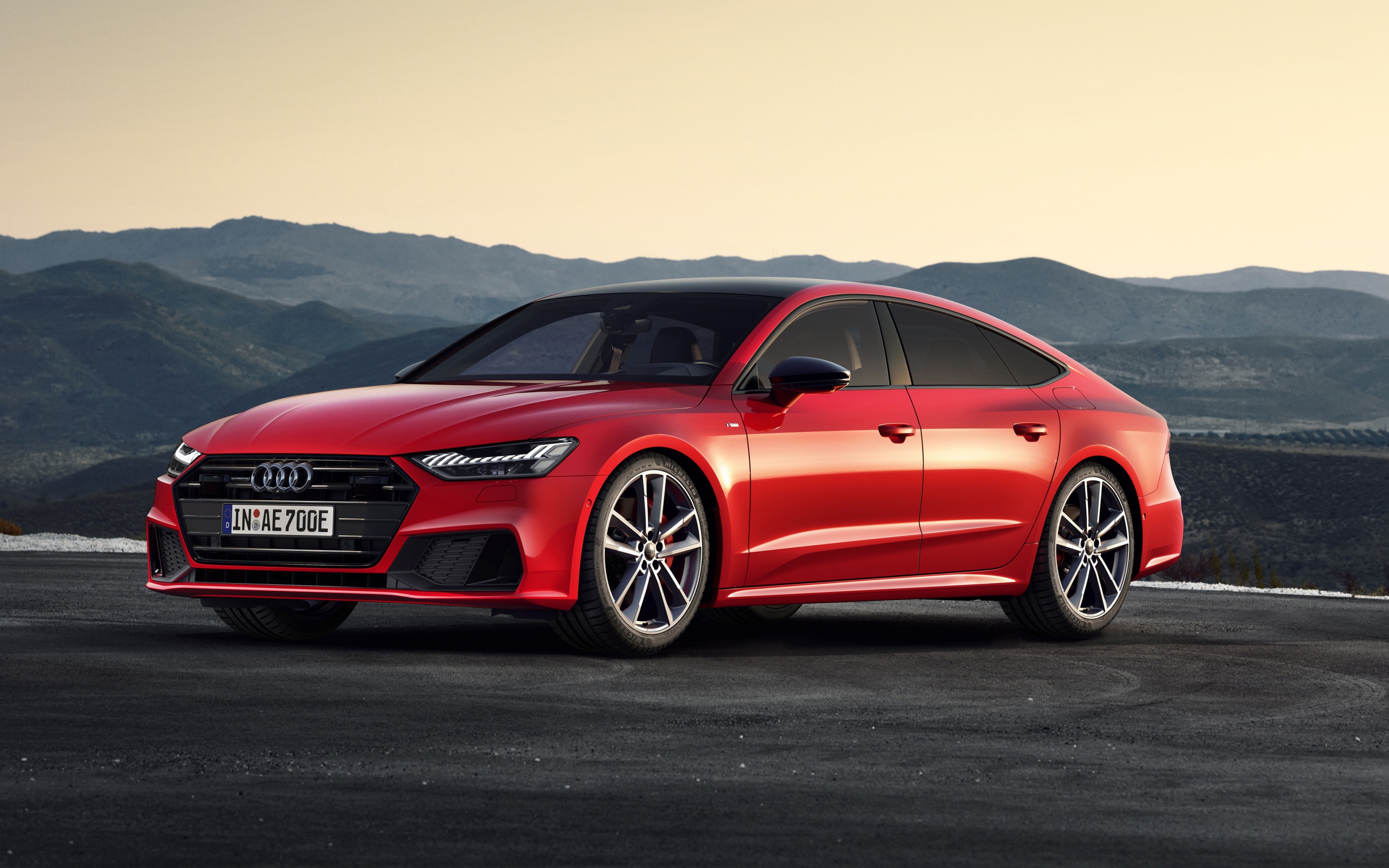 Красный автомобиль Audi A7 Sportback 55 TFSI E Quattro S Line 2019 года в горах