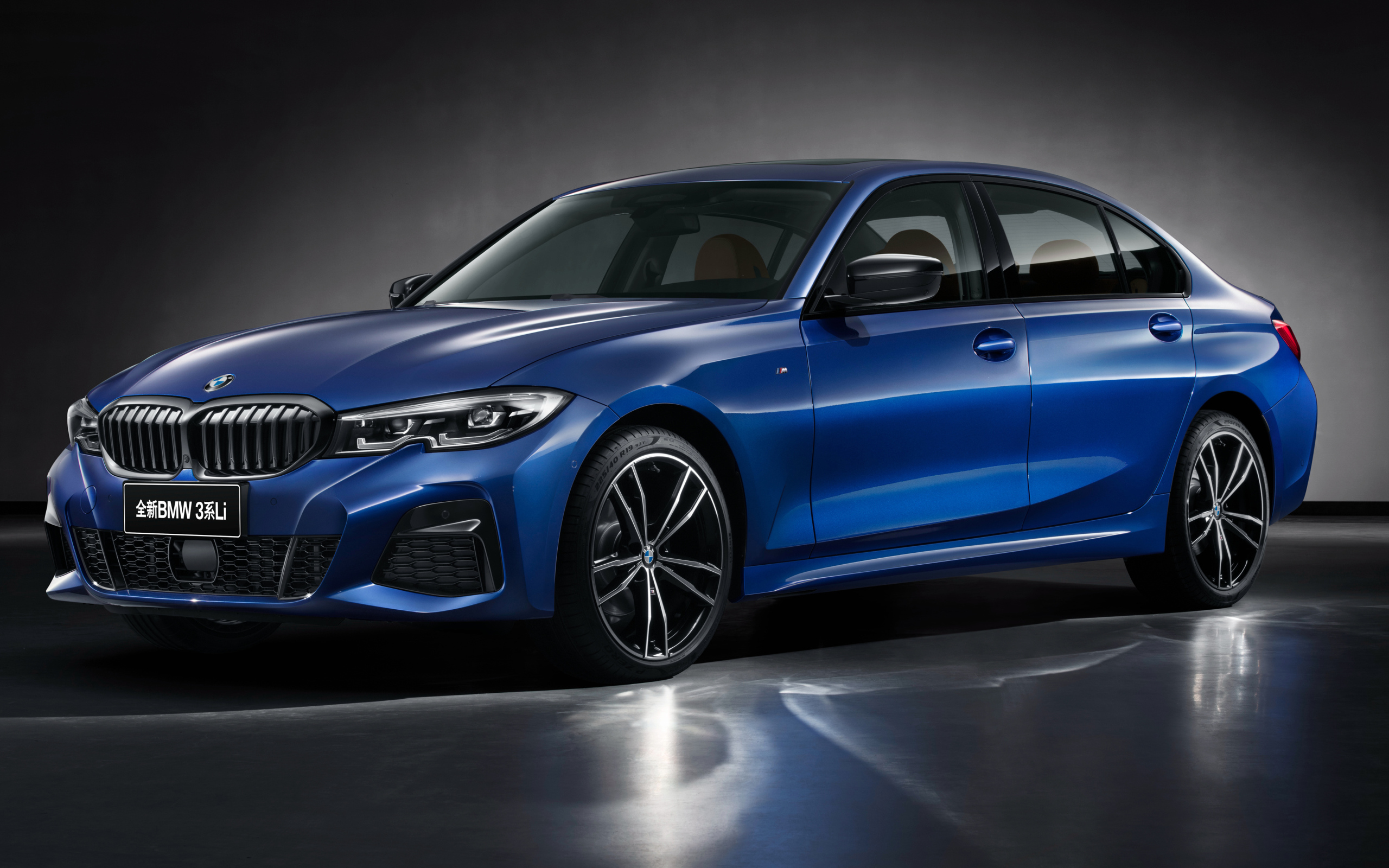 Голубой автомобиль BMW 325Li M Sport 2019 года на сером фоне