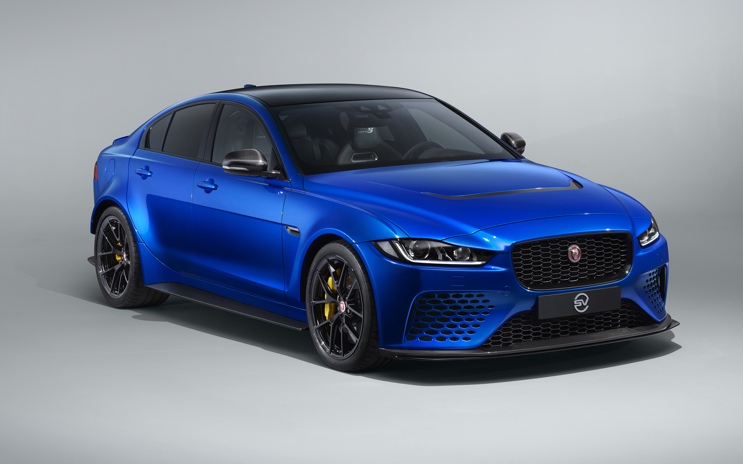 Синий автомобиль Jaguar XE SV Project 8 Touring, 2019 года на сером фоне