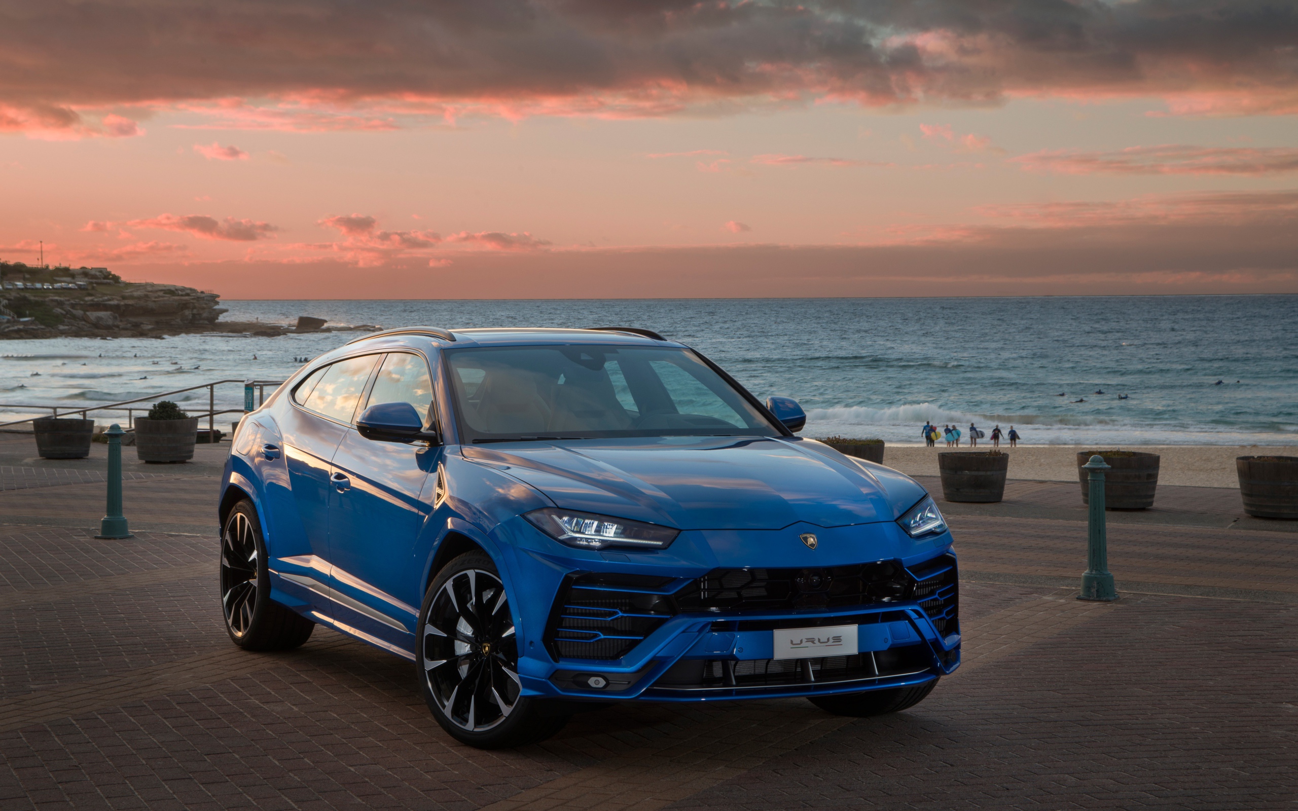 Синий автомобиль Lamborghini Urus под пасмурным небом на берегу  океана