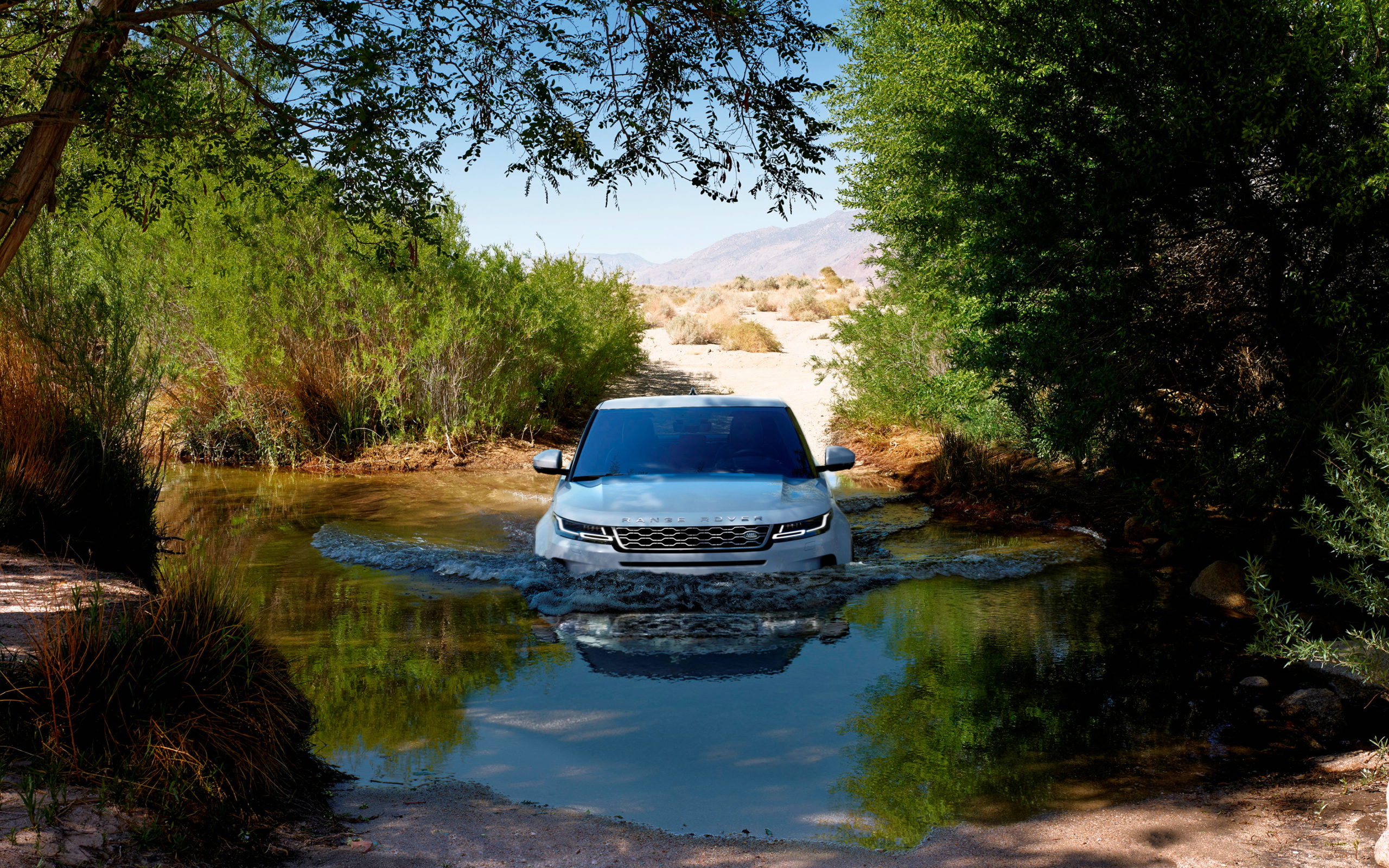 Белый внедорожник Range Rover Evoque едет по воде 