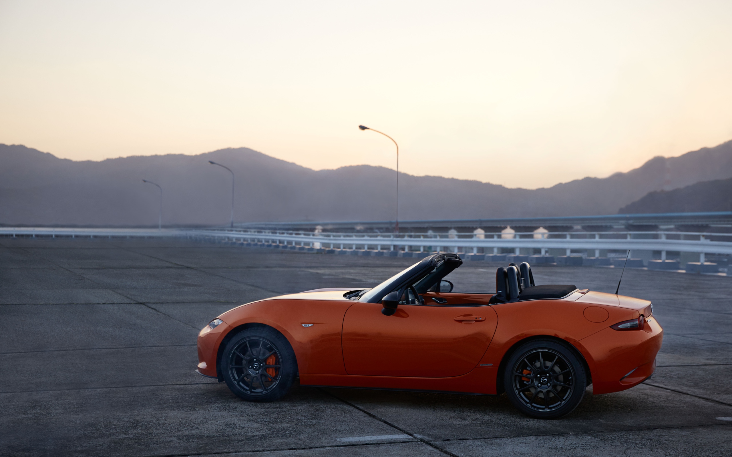 Оранжевый автомобиль кабриолет Mazda MX-5 на фоне неба