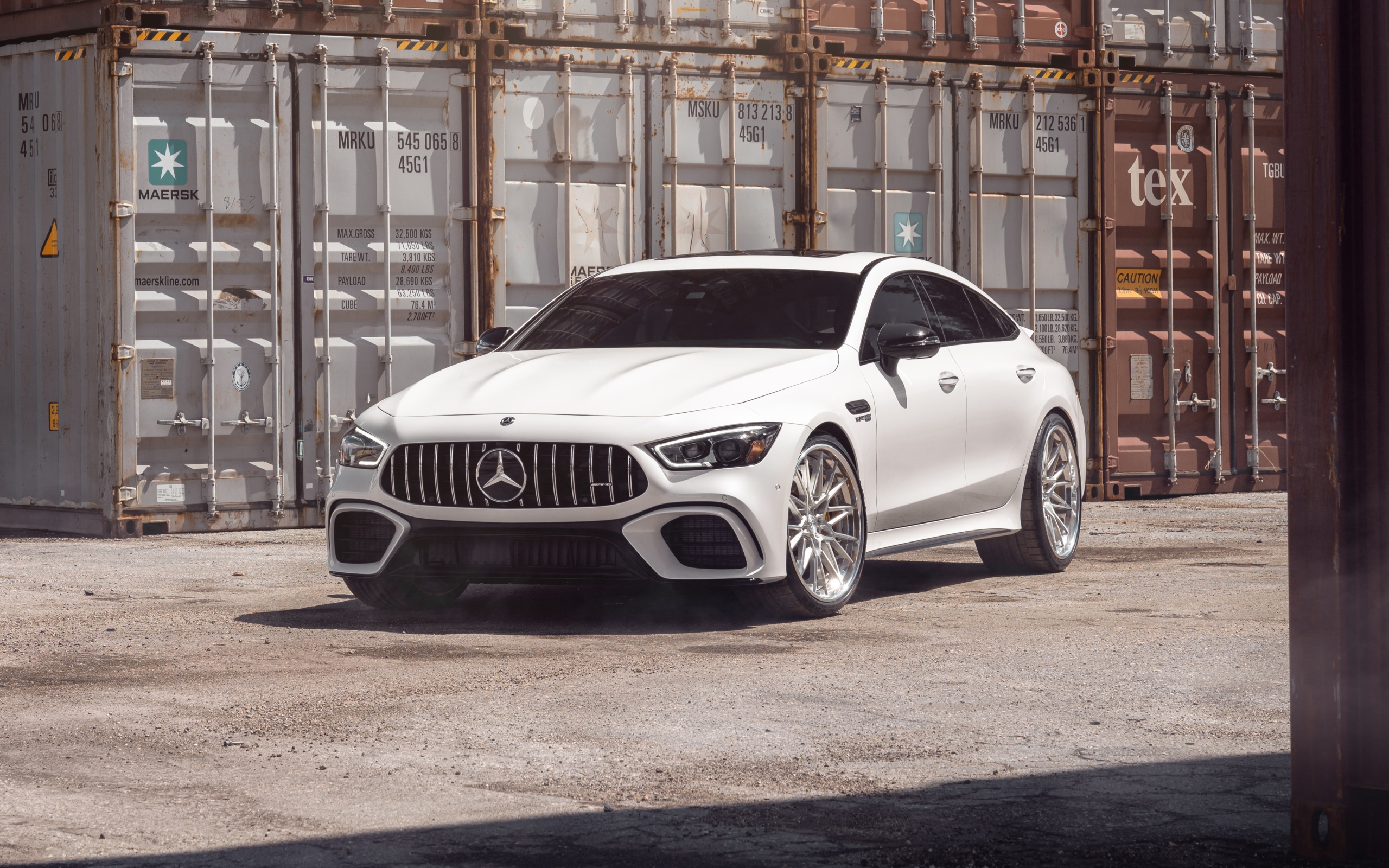 Белый автомобиль Mercedes-AMG GT 63 S стоит у контейнеров