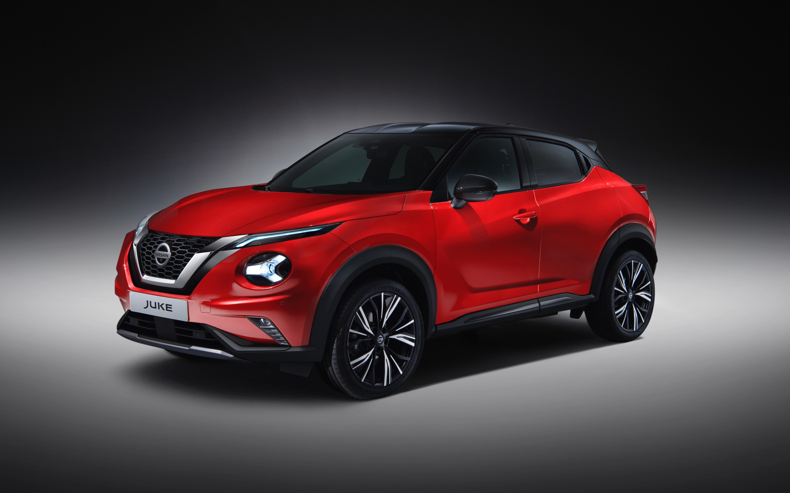 Красный автомобиль Nissan Juke 2019 года на сером фоне