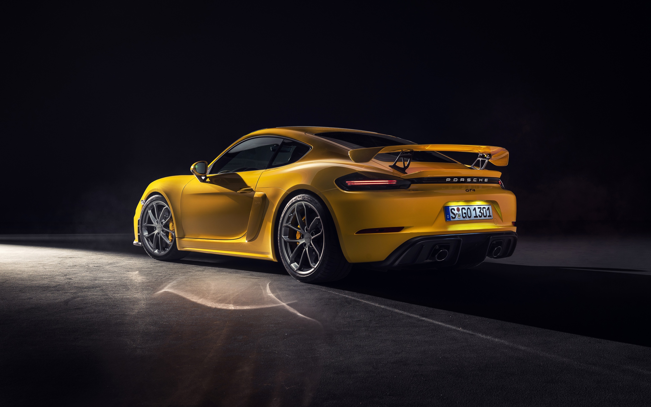 Желтый автомобиль Porsche 718 Cayman GT4, 2019 года вид сзади