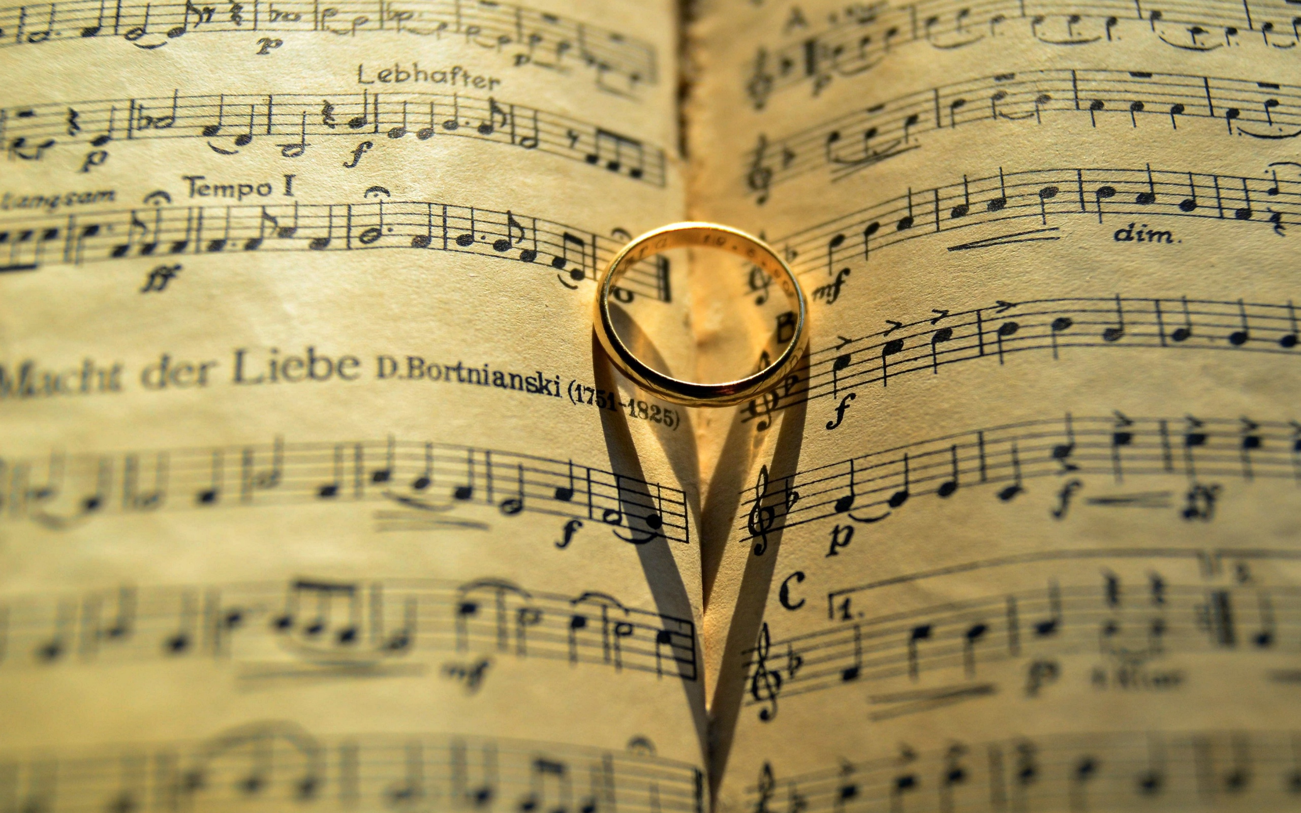 Золотое обручальное кольцо лежит на нотной тетради