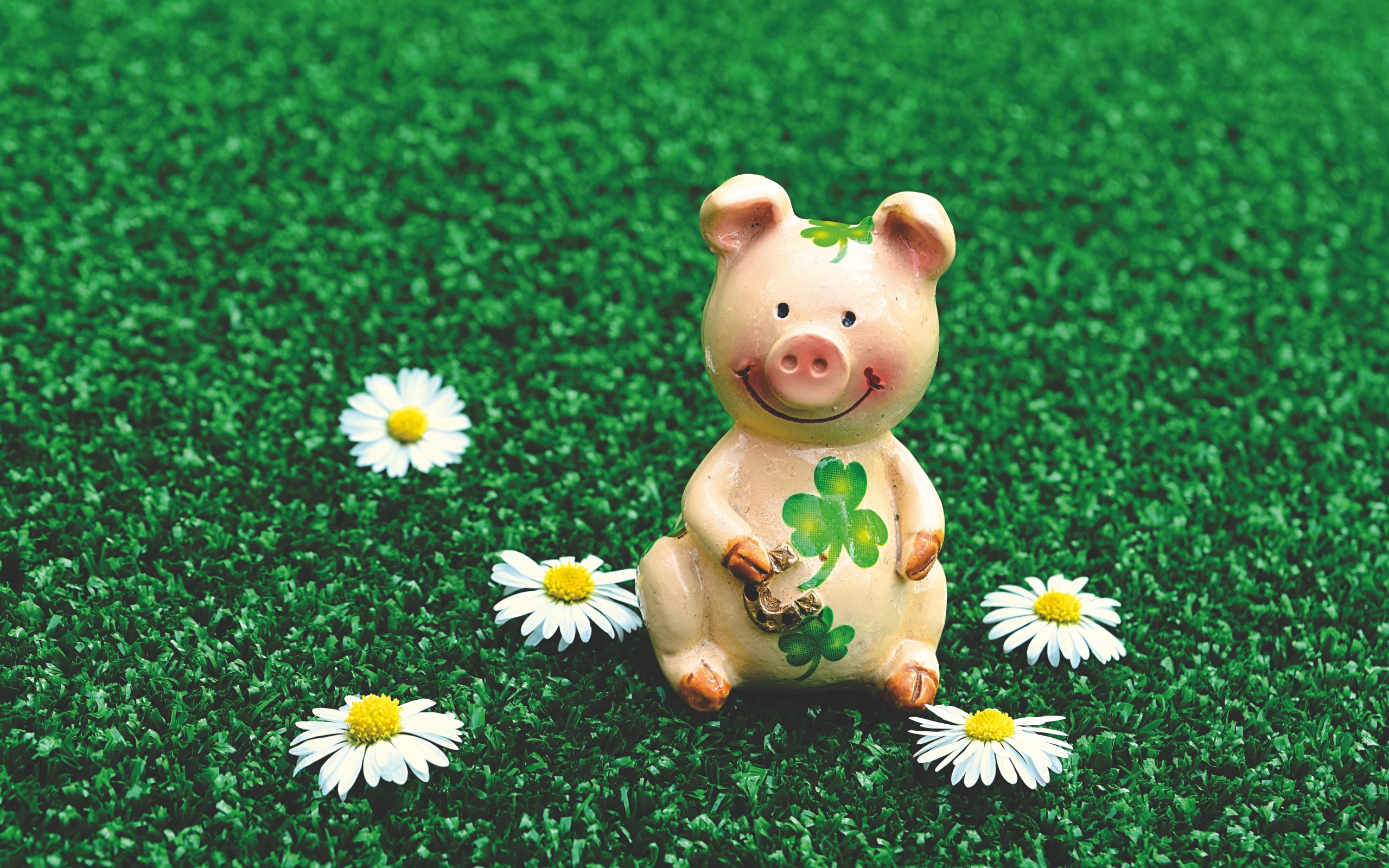 Статуэтка поросенка на зеленой траве с ромашками