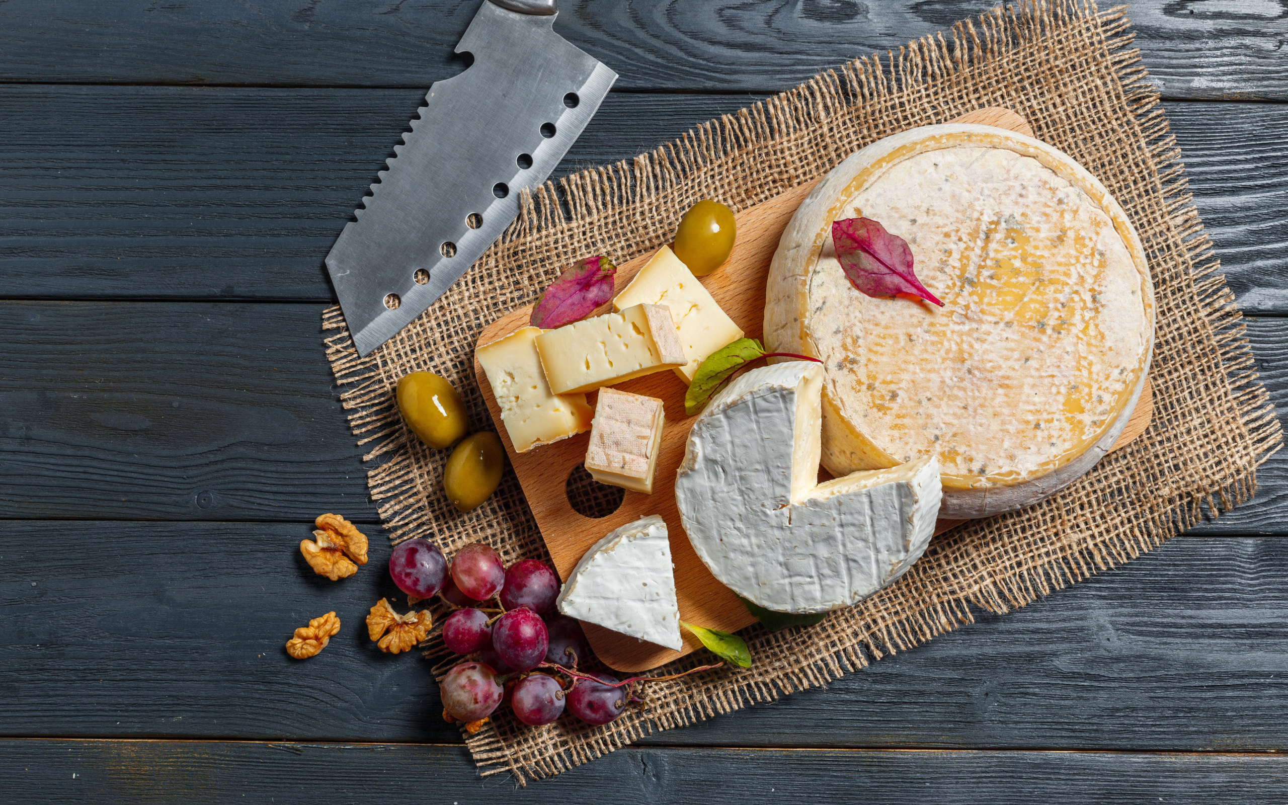 Сыр с плесенью на столе с орехами и виноградом 