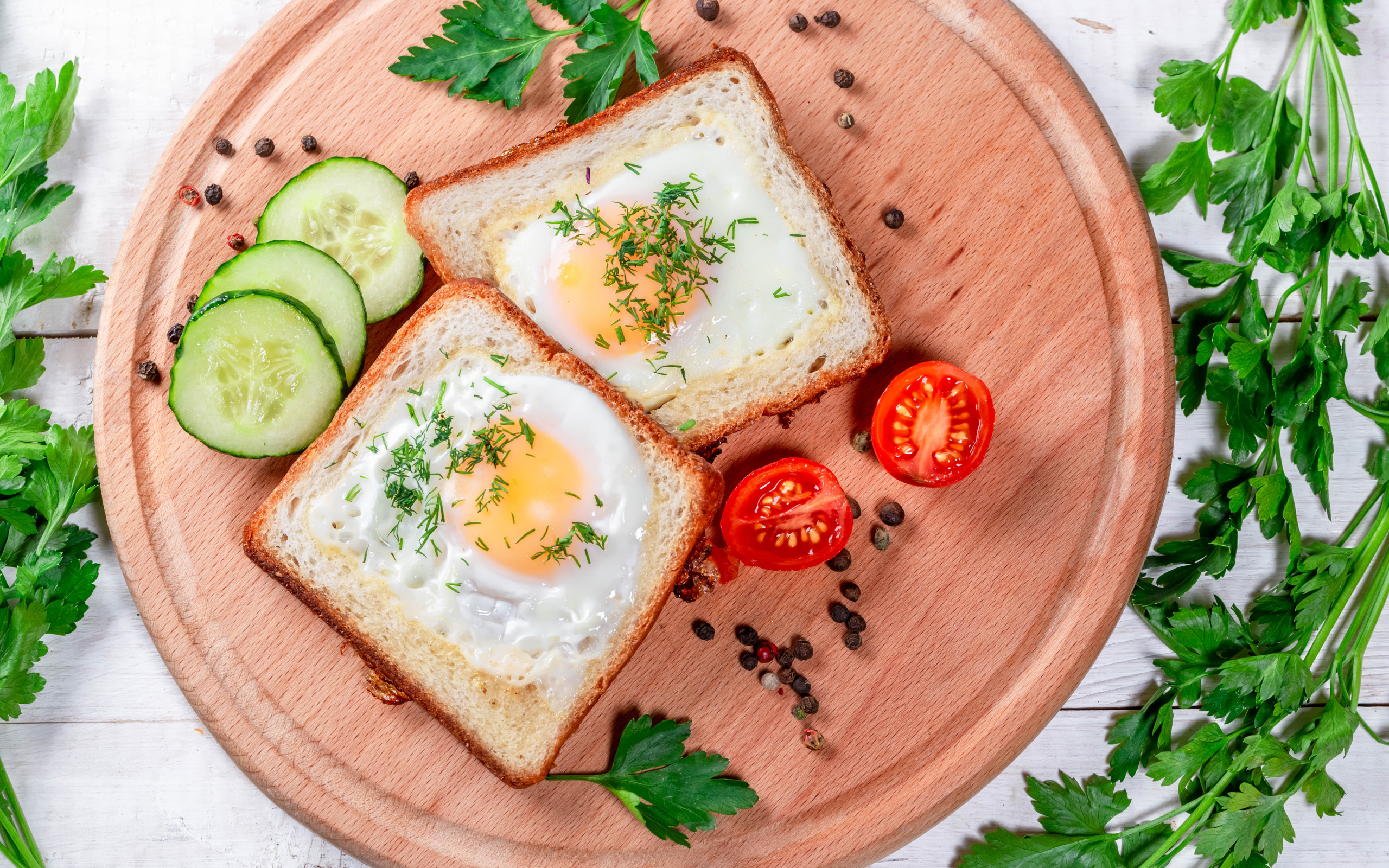 Яичница в хлебе на доске с помидорами, огурцами и петрушкой