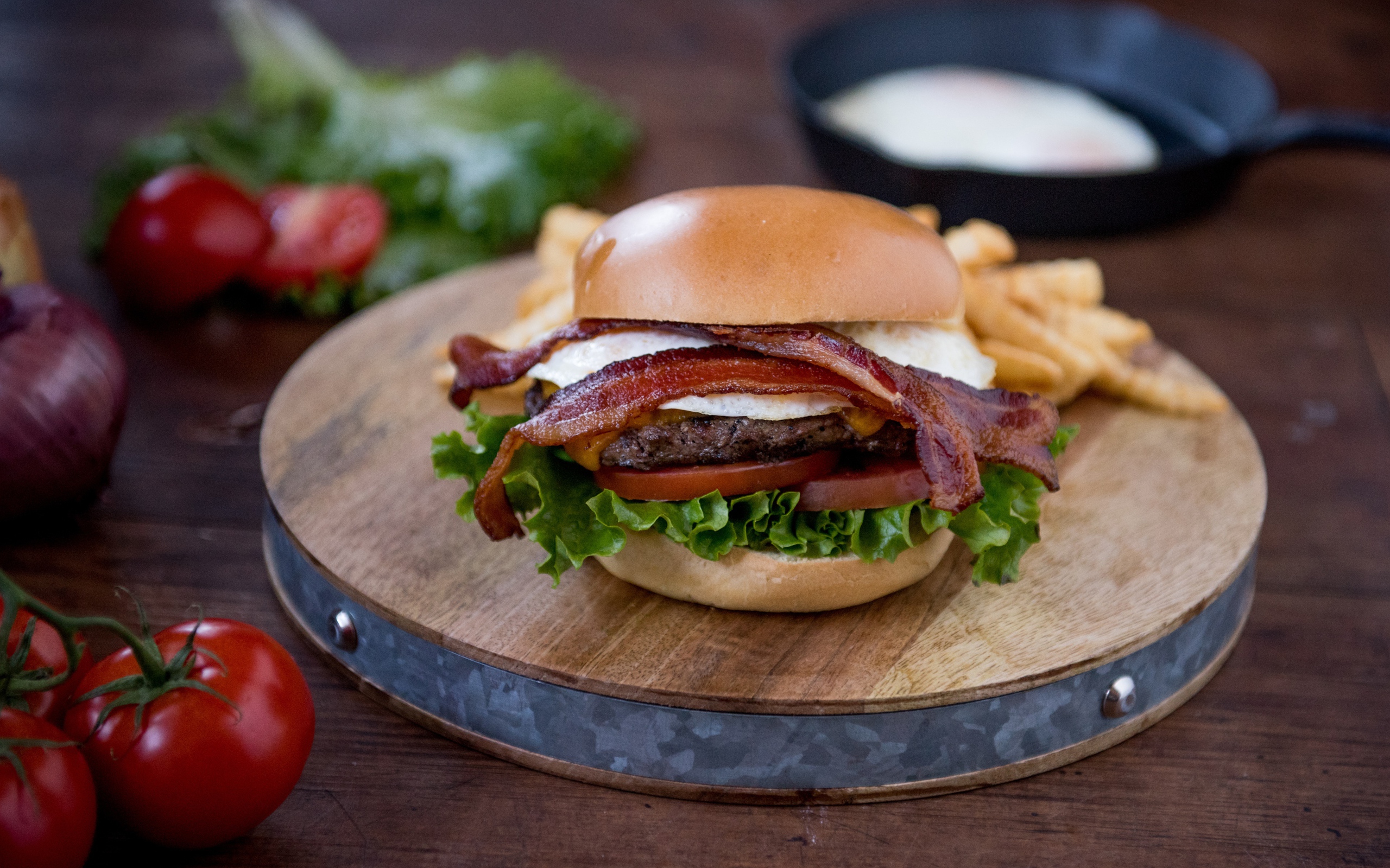 Гамбургер с беконом на столе с овощами