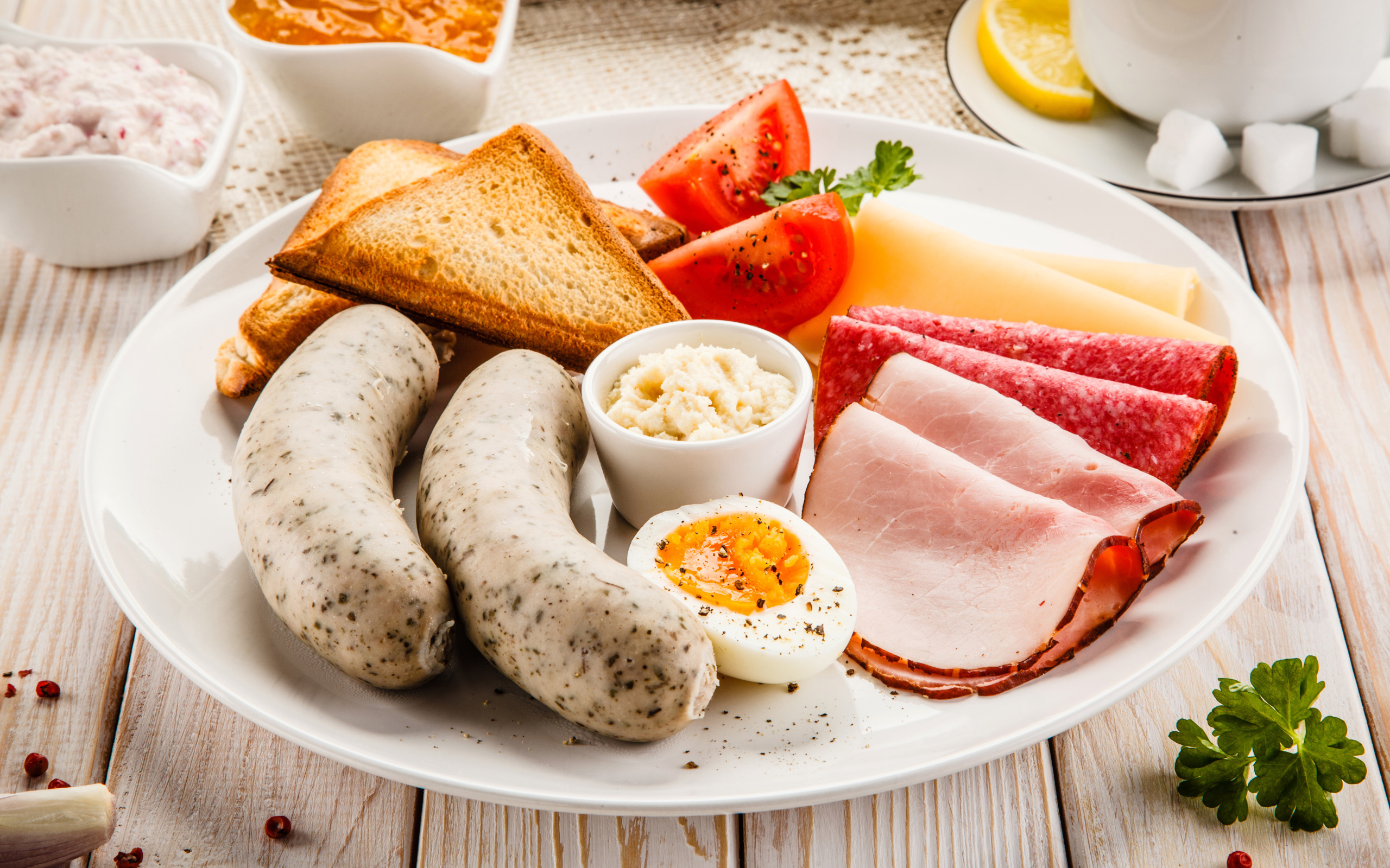 Большая белая тарелка с колбасой, яйцами, помидорами, тостами и сыром