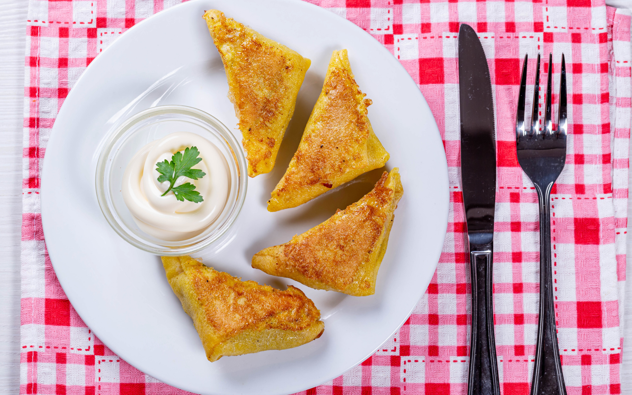 Блинчики со сметаной на столе со столовыми приборами 