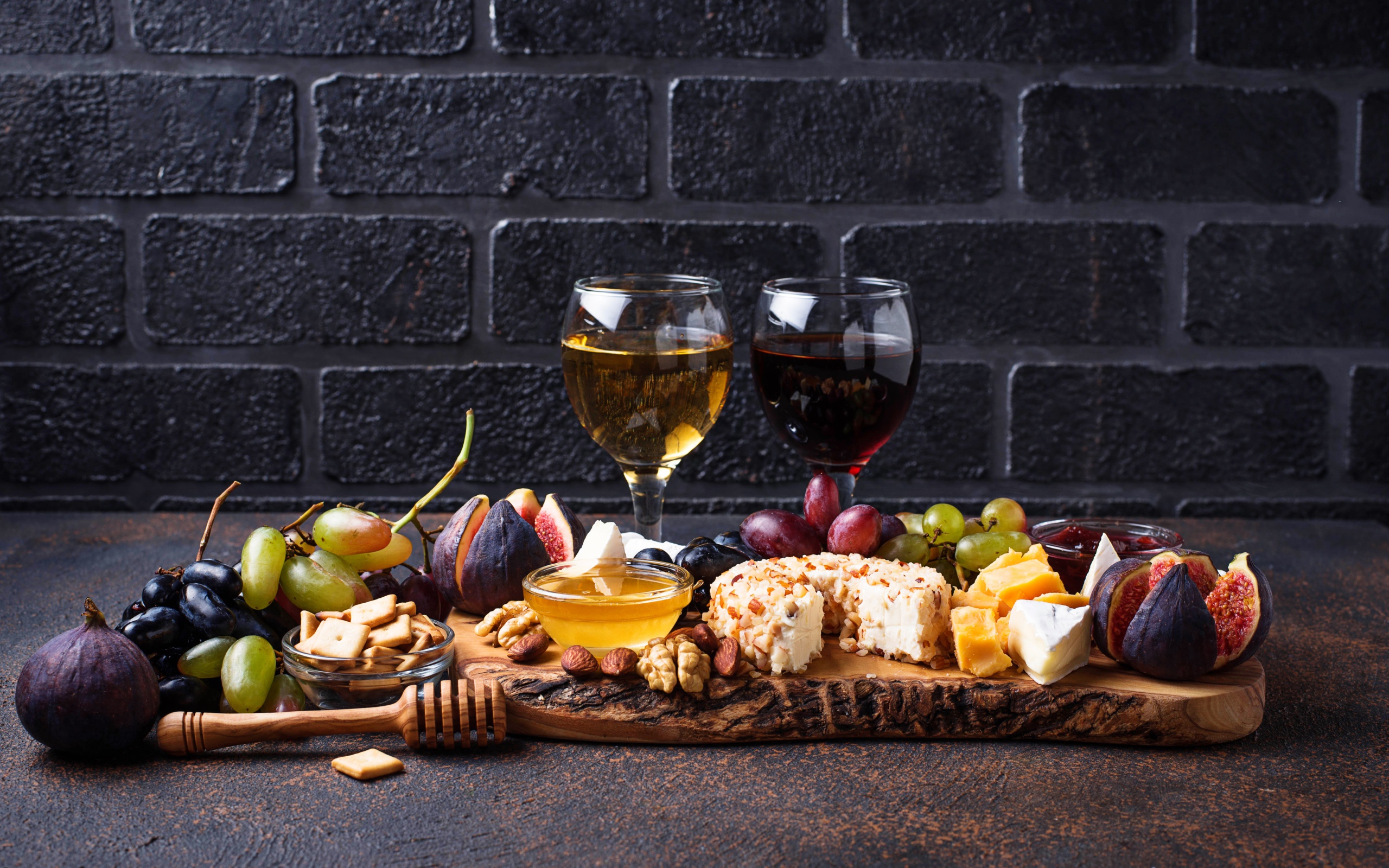 Два бокала вина на столе с сыром, инжиром и виноградом