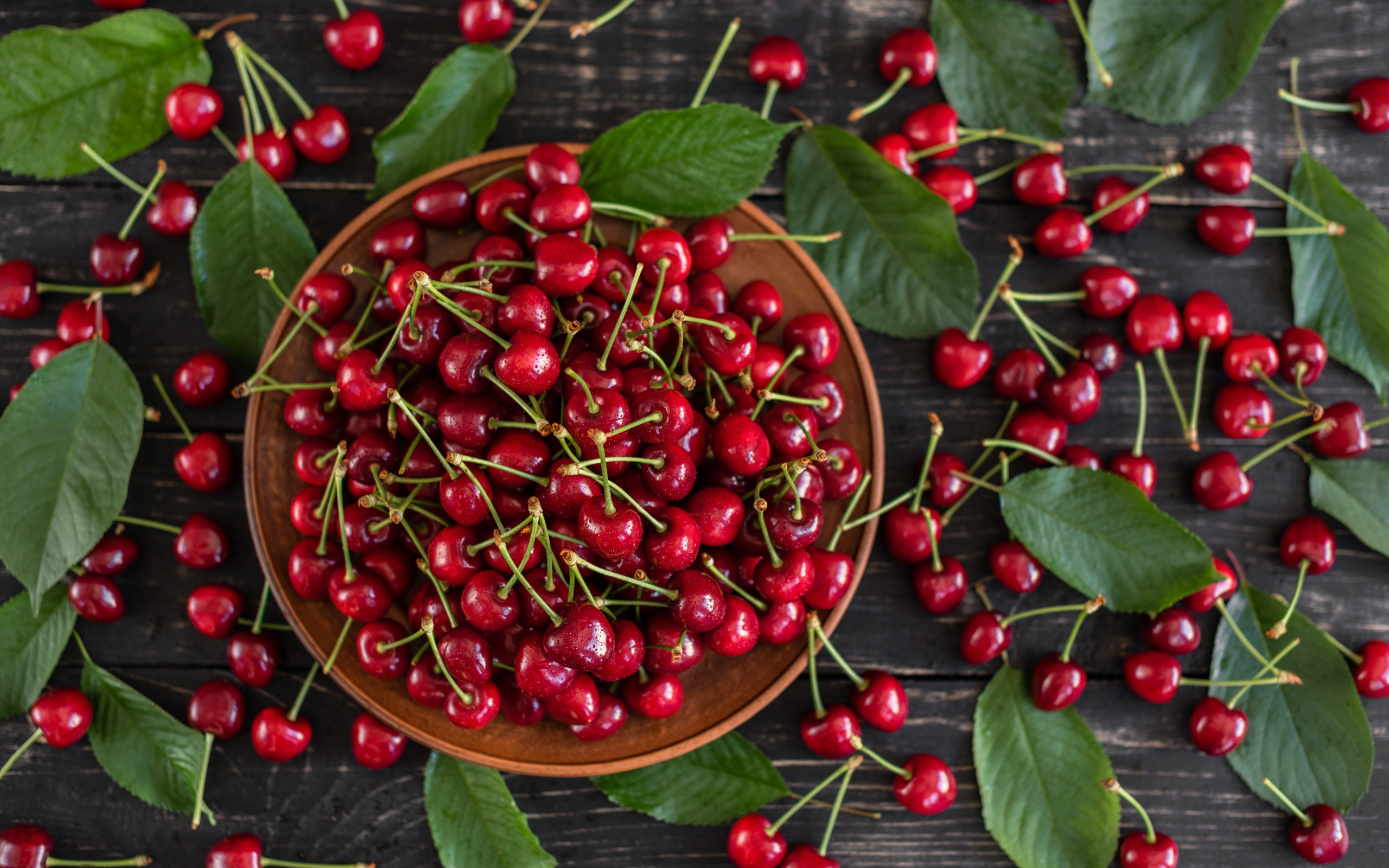 Много спелой красной черешне в миске на столе