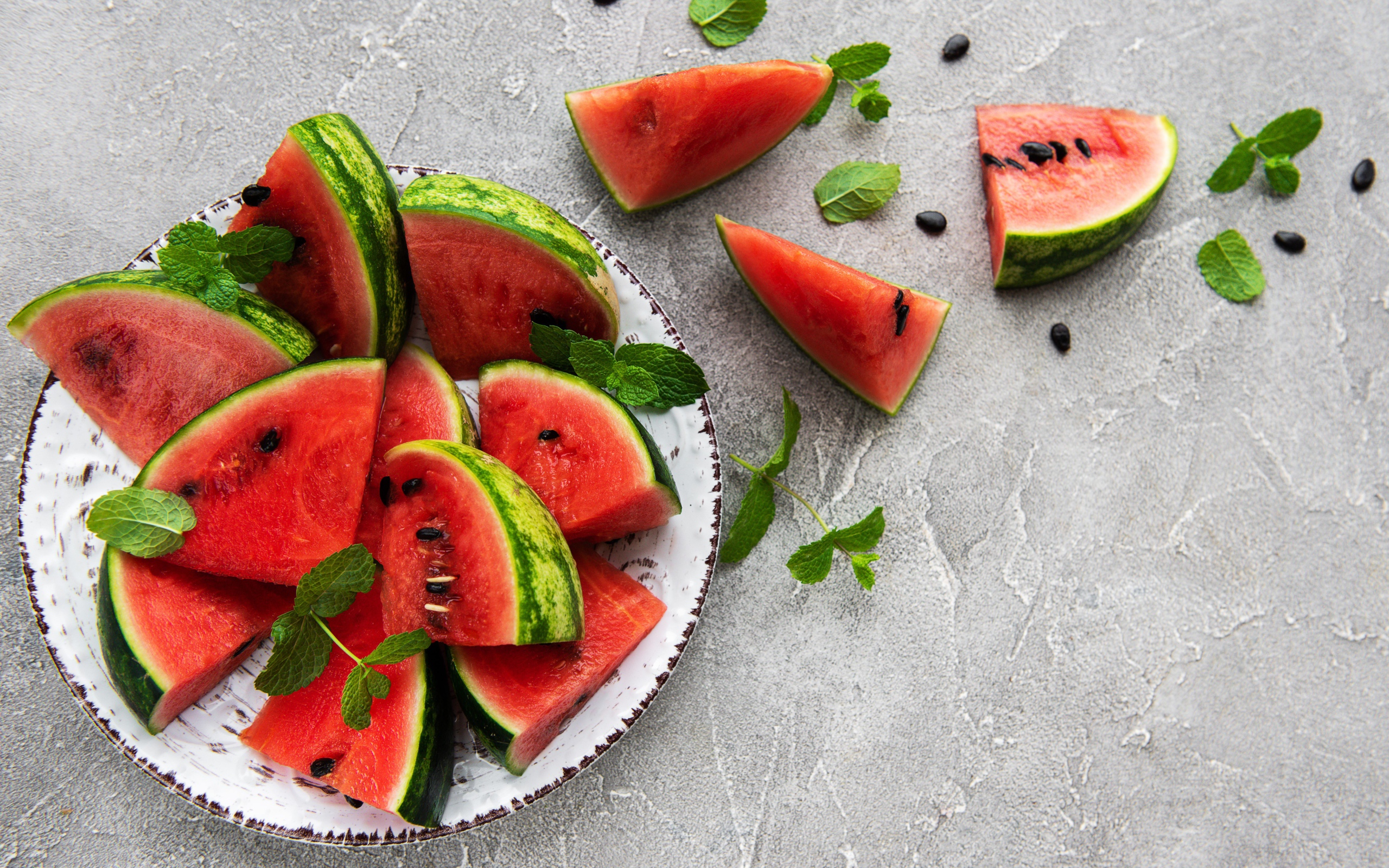 Полосатый арбуз нарезан кусочками на тарелке