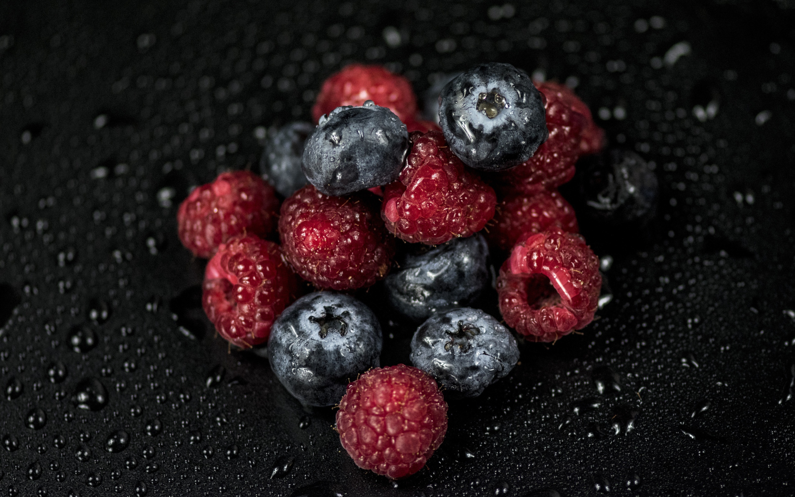 Мокрые ягоды черники и малины на черном фоне