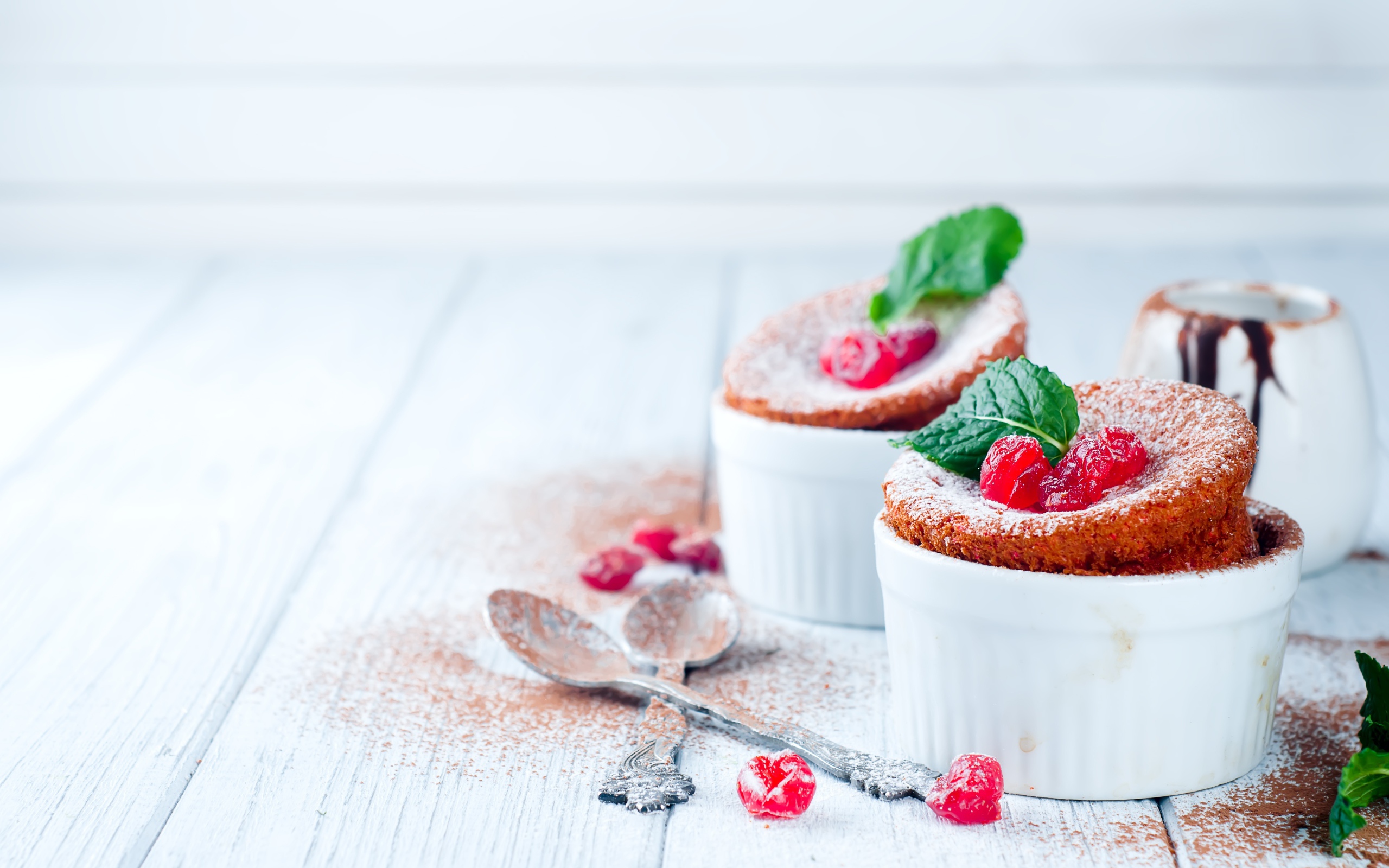 Пирожное с ягодами и сахарной пудрой на столе с ложками