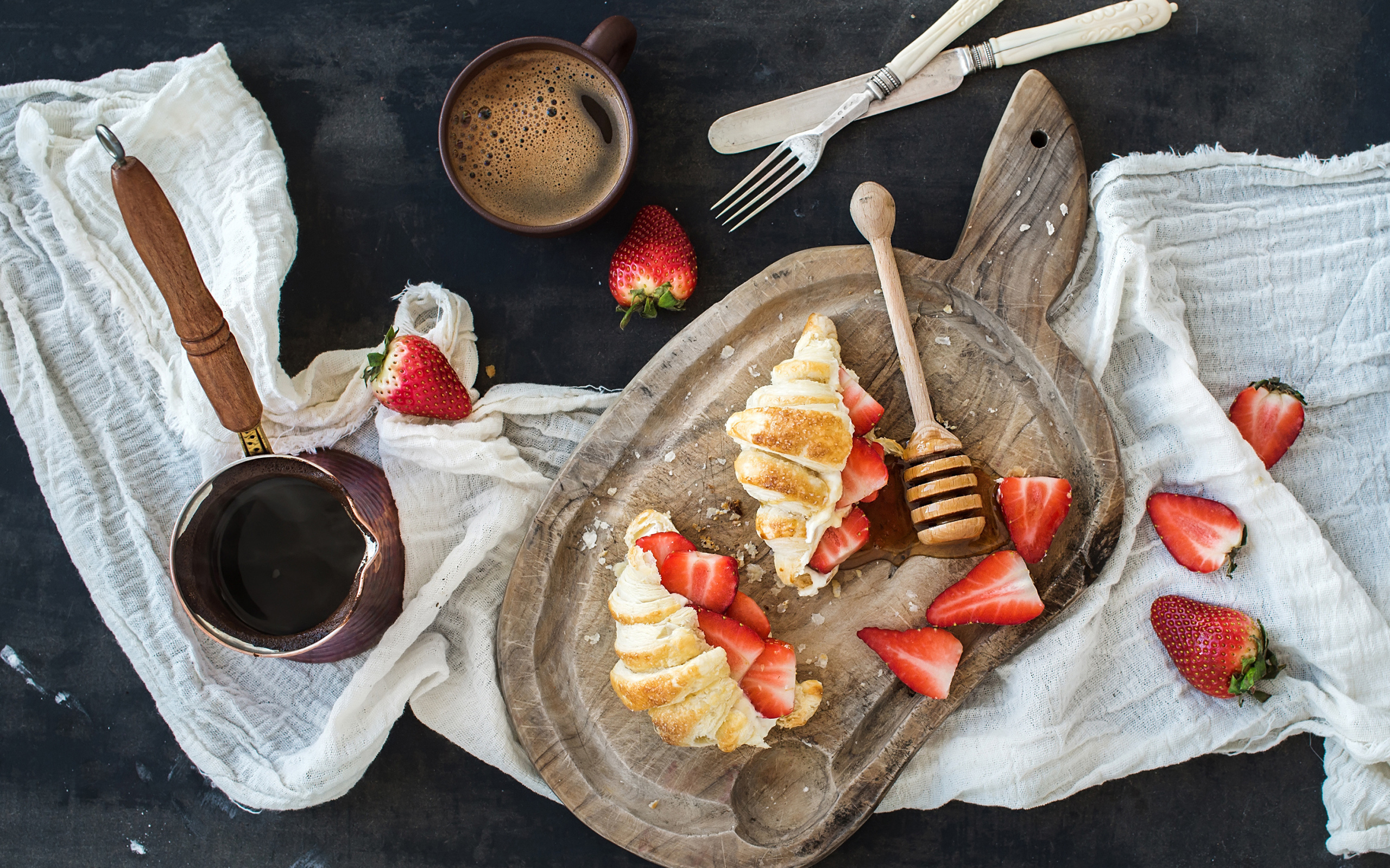 Круассаны на доске с клубникой и медом