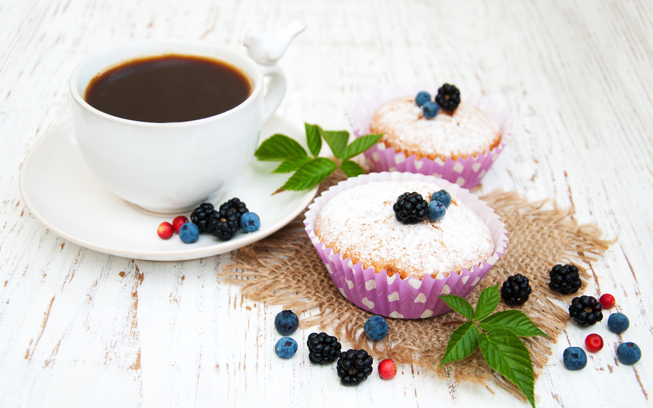 Кексы с сахарной пудрой и ягодами на столе с какао