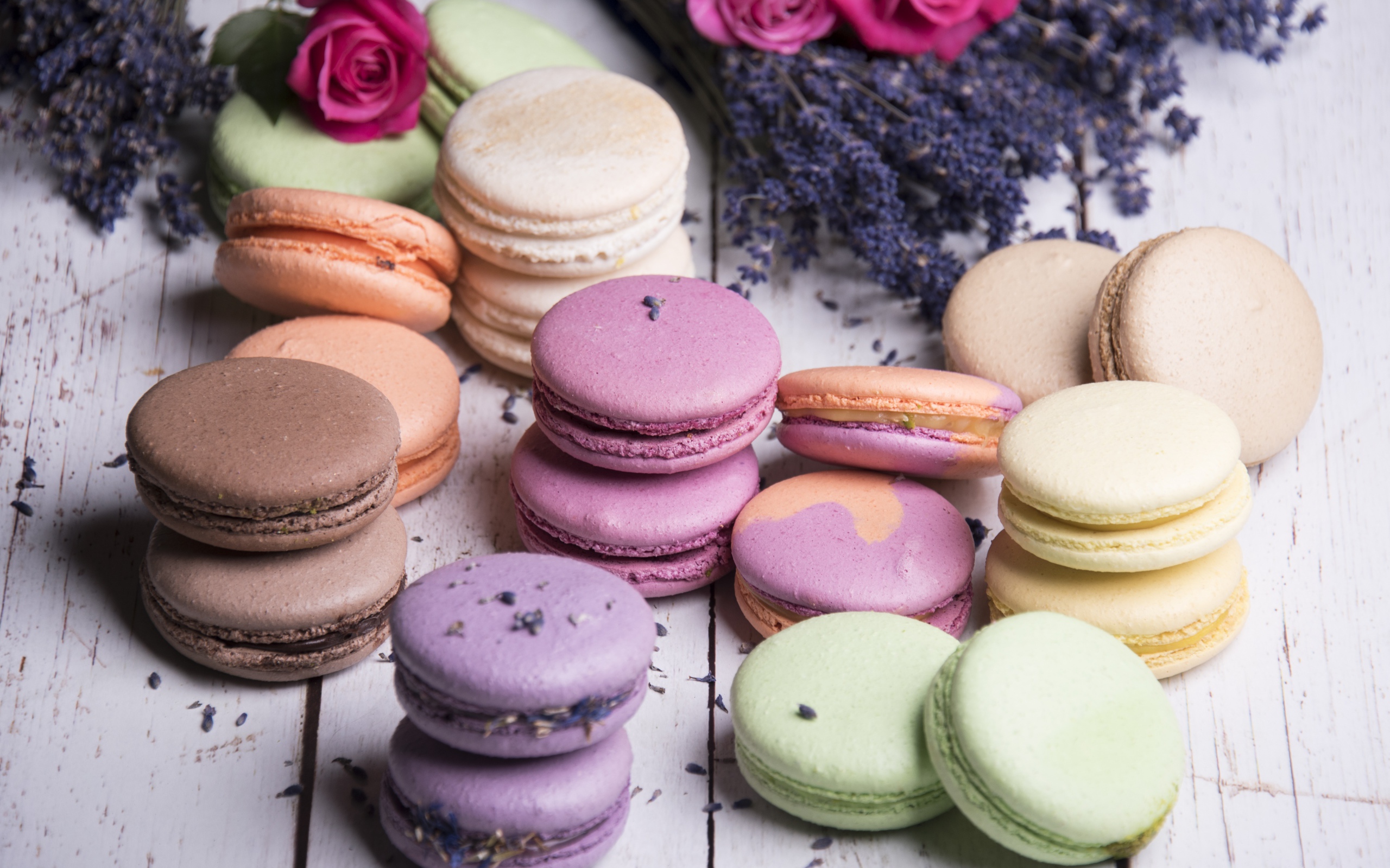 Разноцветный десерт макарон на столе с лавандой и розами