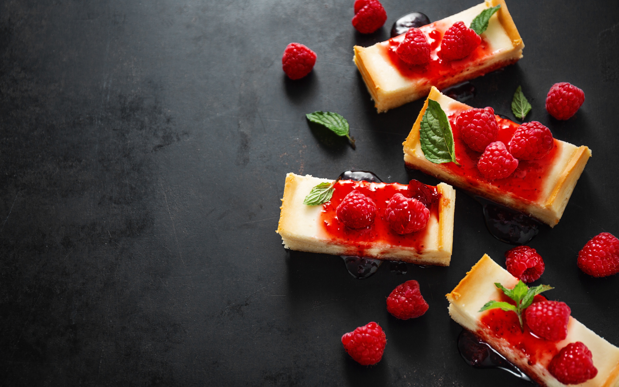 Куски чизкейка на столе с джемом и ягодами малины