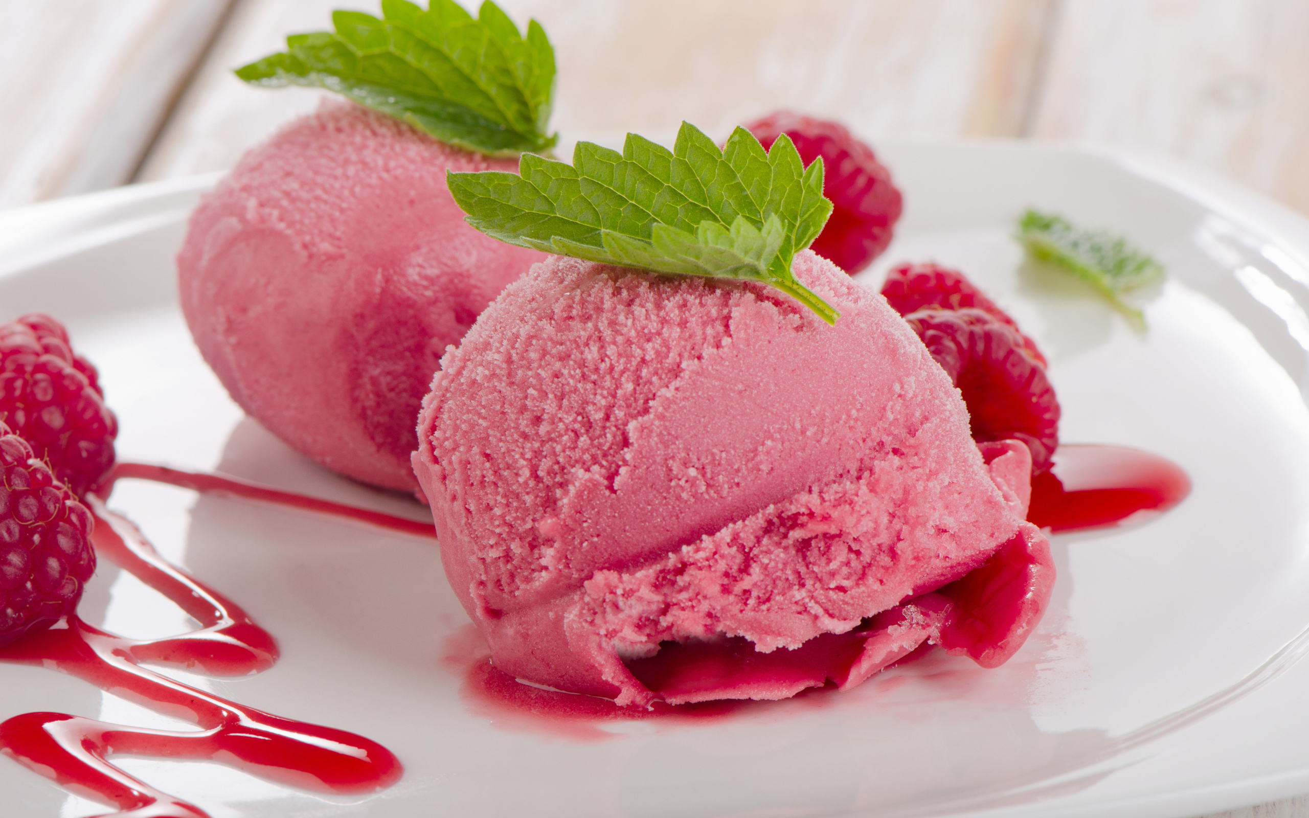 Два шарика малинового мороженого на тарелке с ягодами 