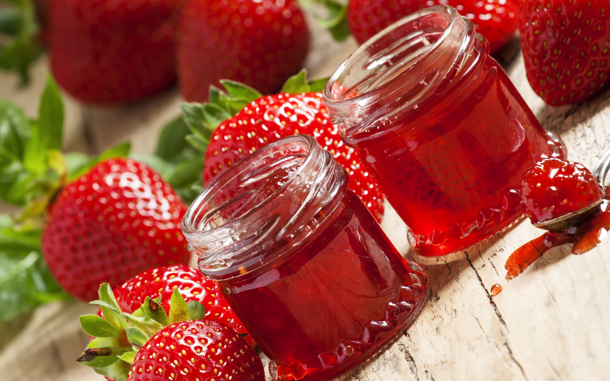Две баночки клубничного джема на столе с клубникой