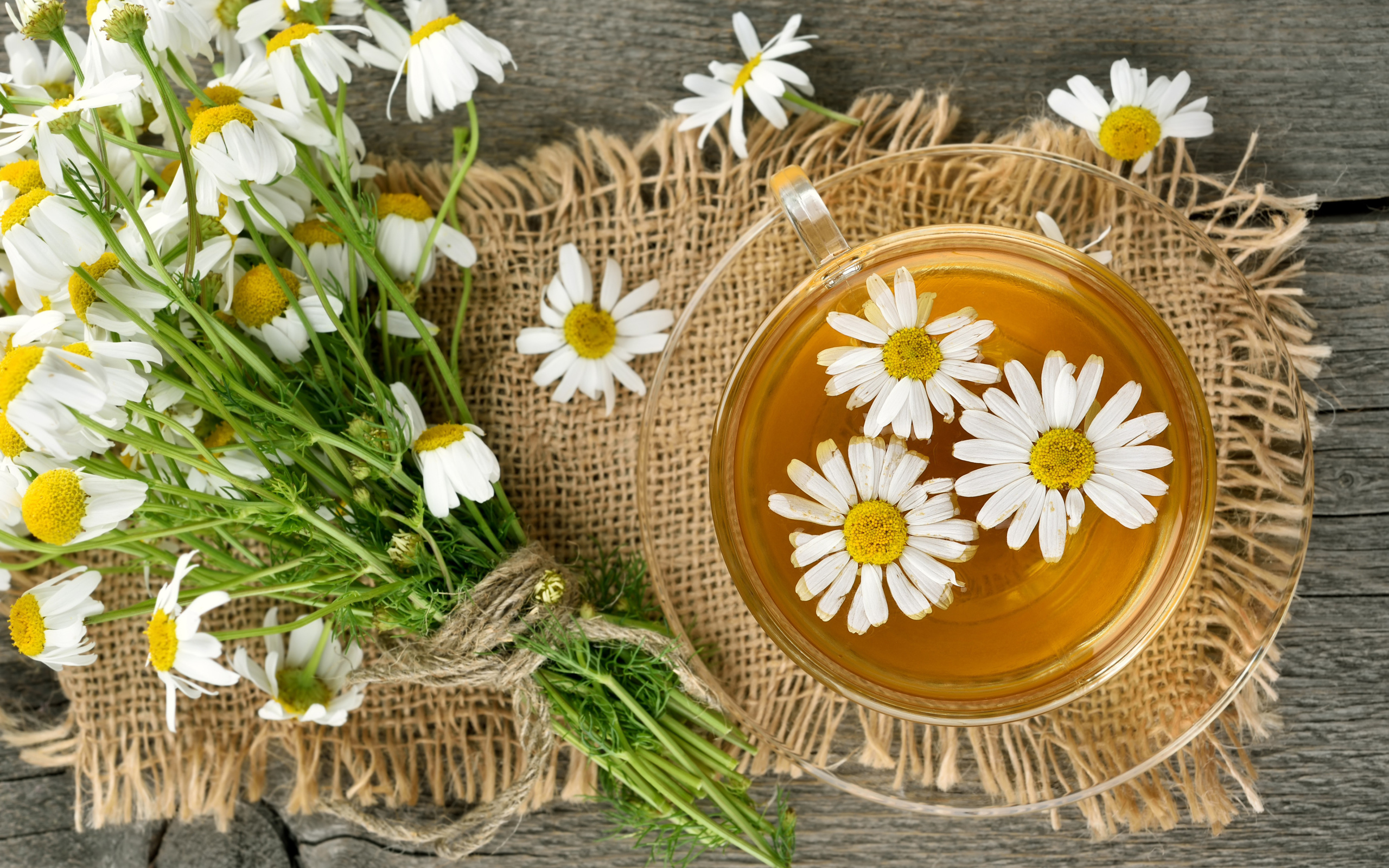 Чай в стеклянной чашке на столе с ромашкой