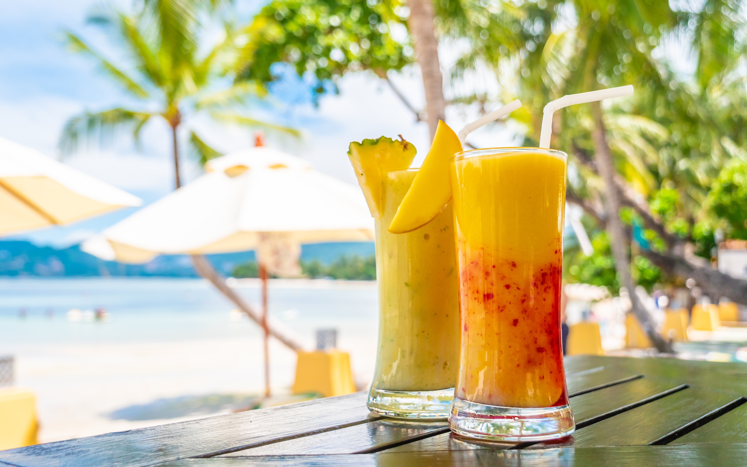 Два цитрусовых коктейля на столе на тропическом пляже