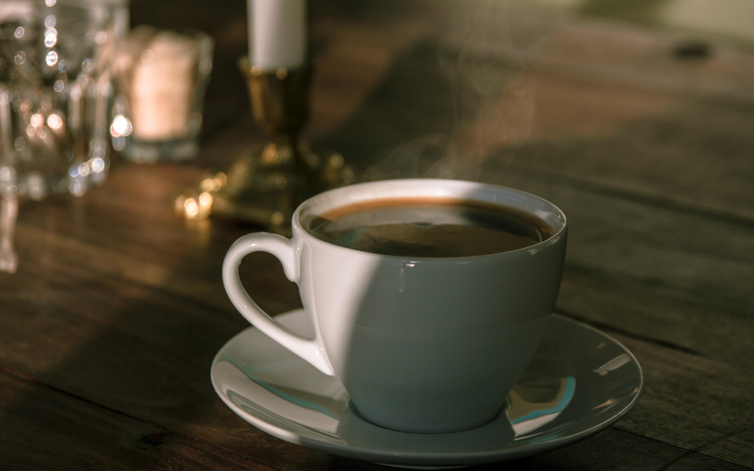 Белая чашка кофе на столе в лучах солнца