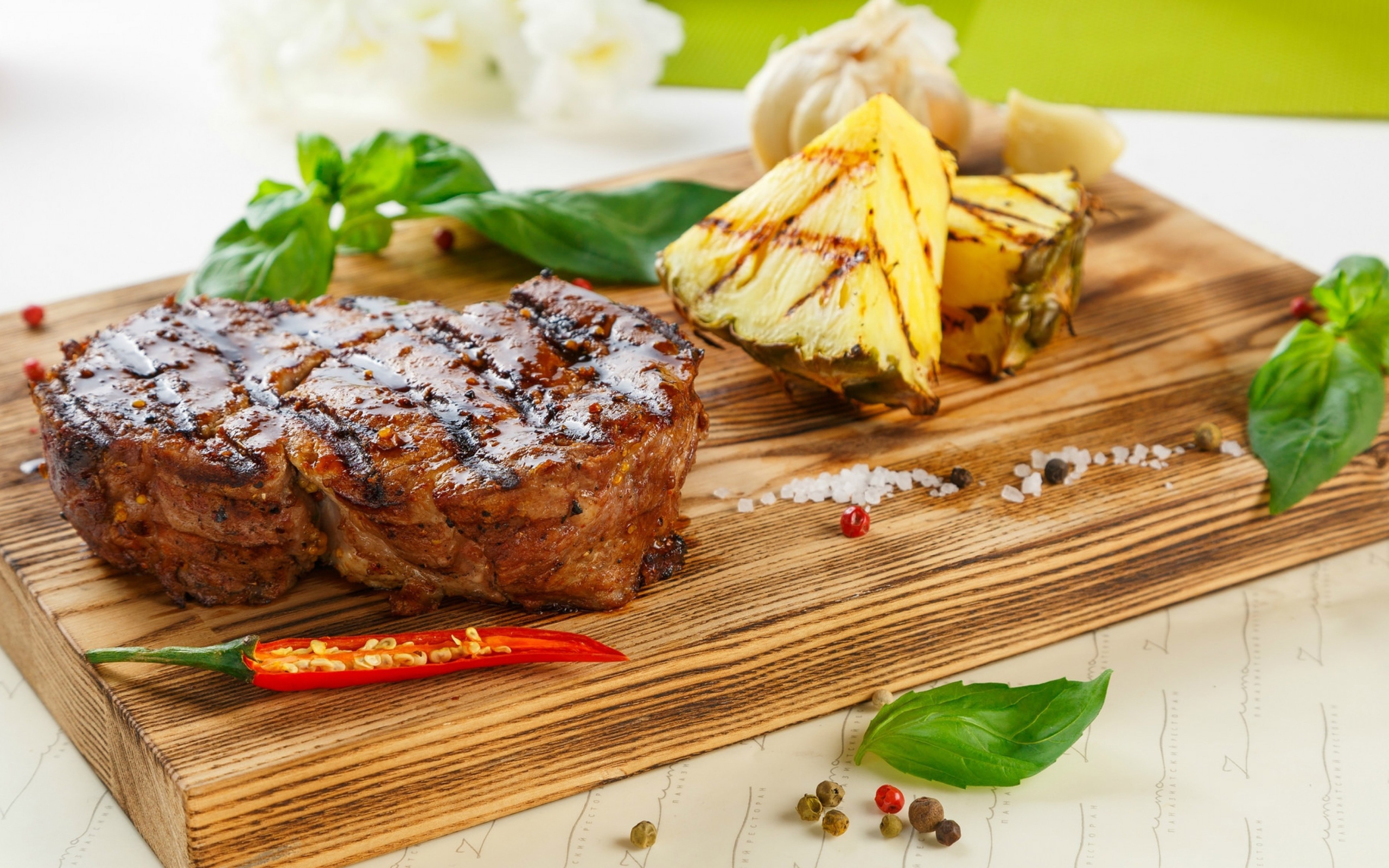 Кусок мяса гриль на деревянной доске с кусочками ананаса и базиликом