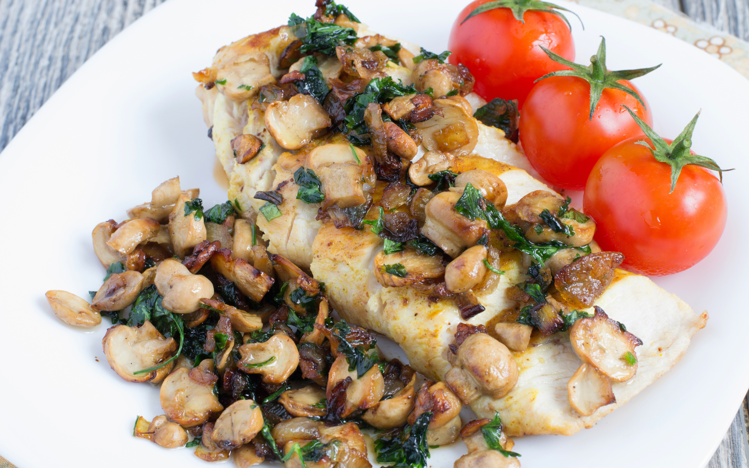 Аппетитный кусок куриного филе с грибами на тарелке с помидорами 