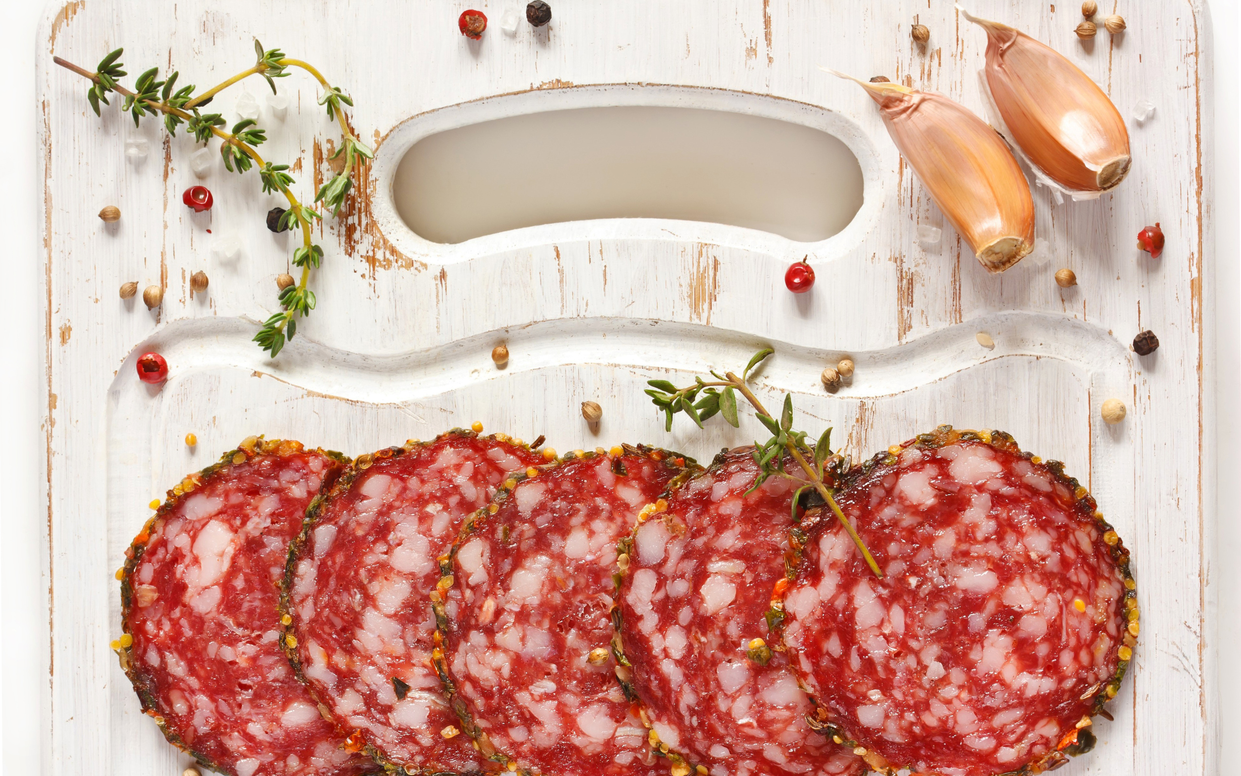 Нарезанная колбаса на разделочной доске со специями и чесноком