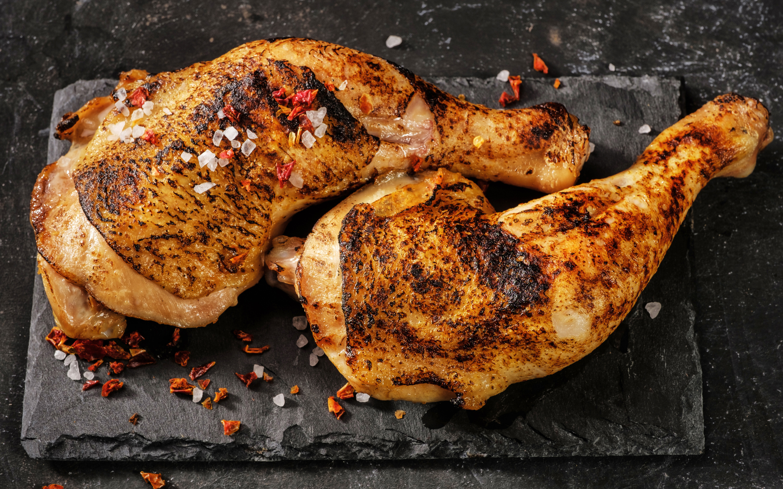 Два запеченных куриных окорочка на черном фоне