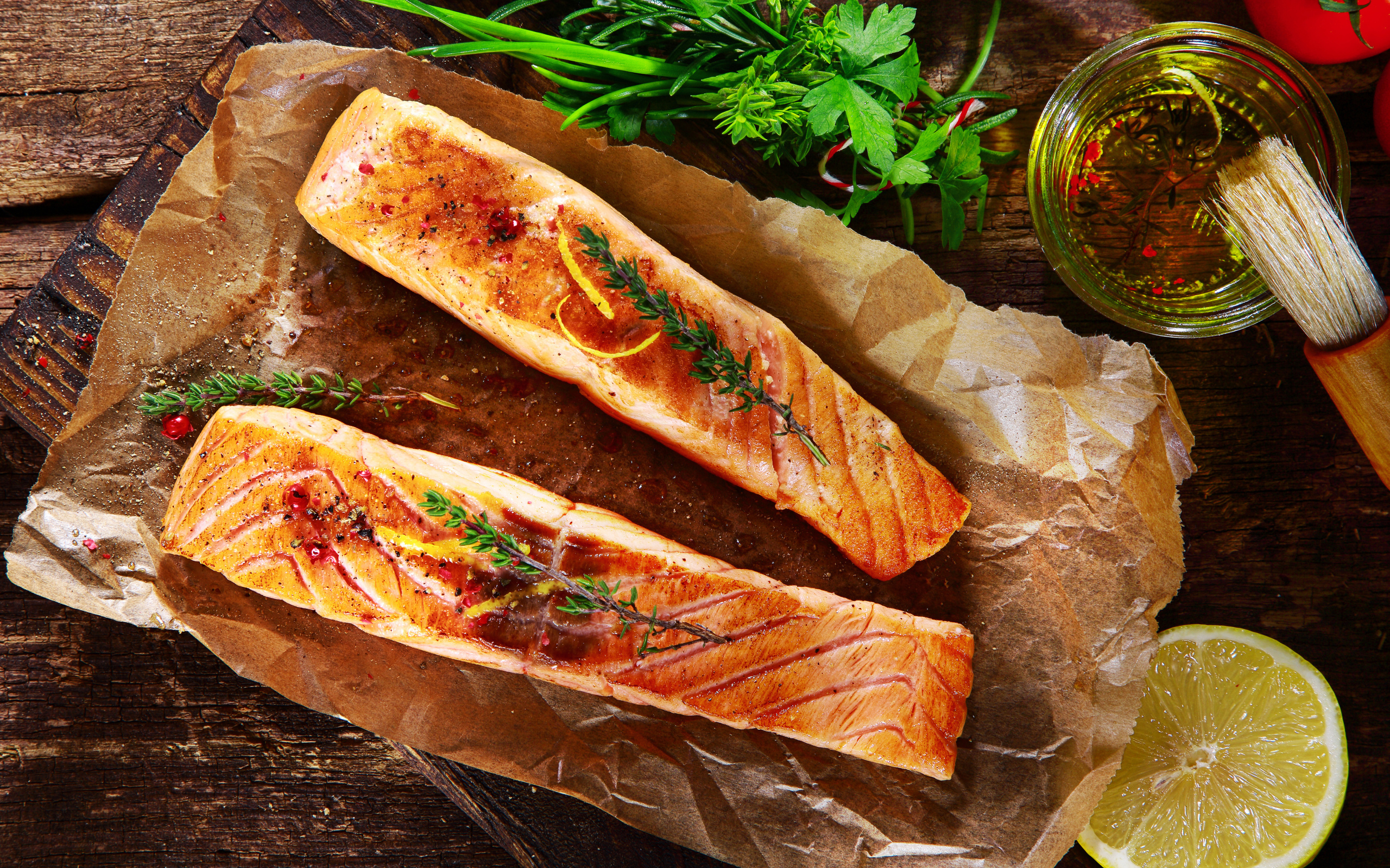 Два куска запеченной рыбы на столе с оливковым маслом и зеленью