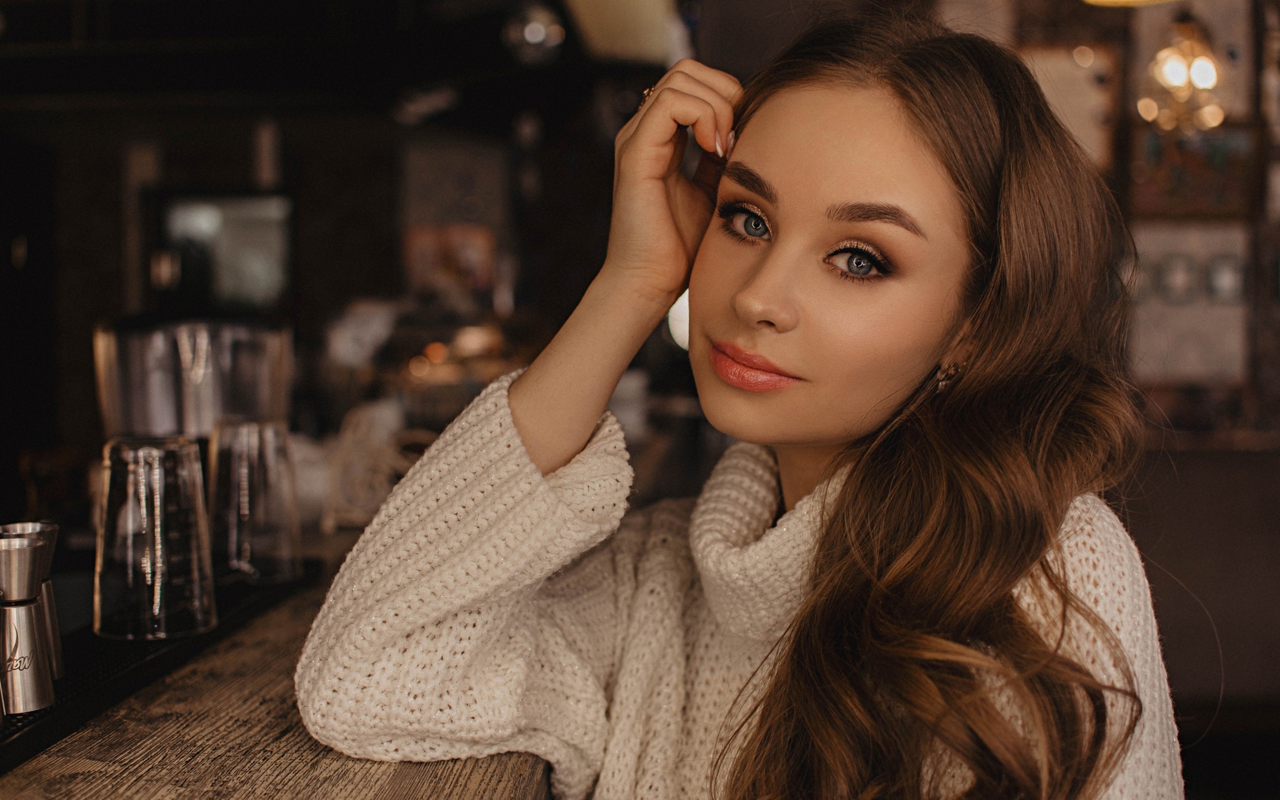 Красивая голубоглазая девушка в белом свитере в кафе