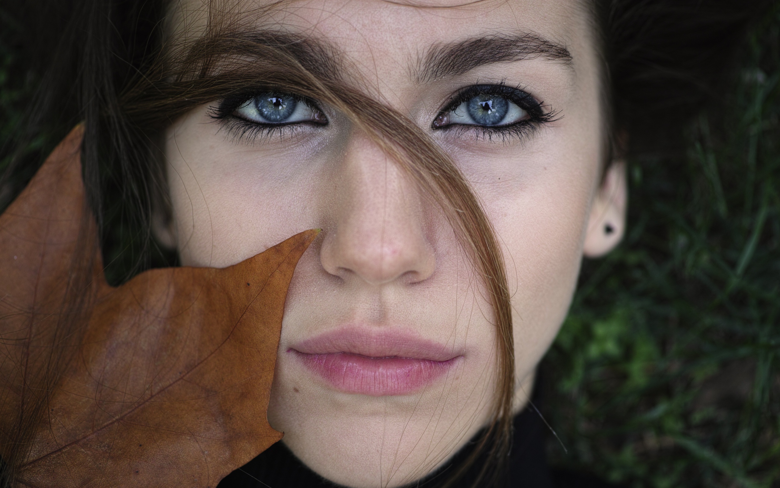 Красивая голубоглазая девушка с желтым листом у лица