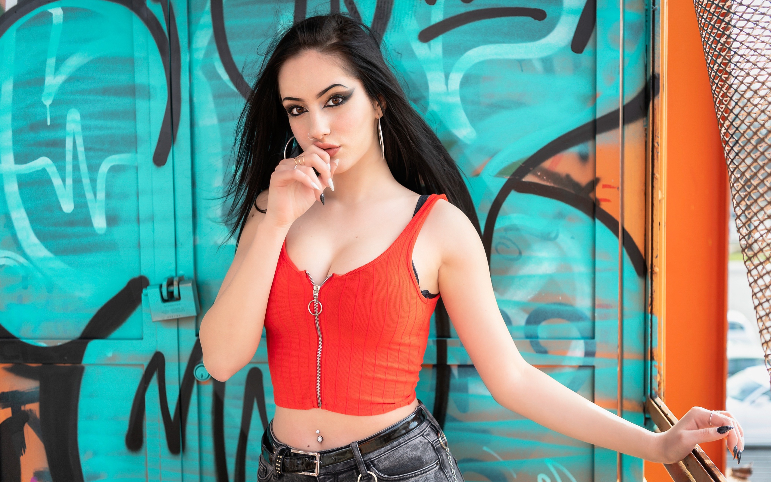 Красивая девушка с пирсингом стоит у стены