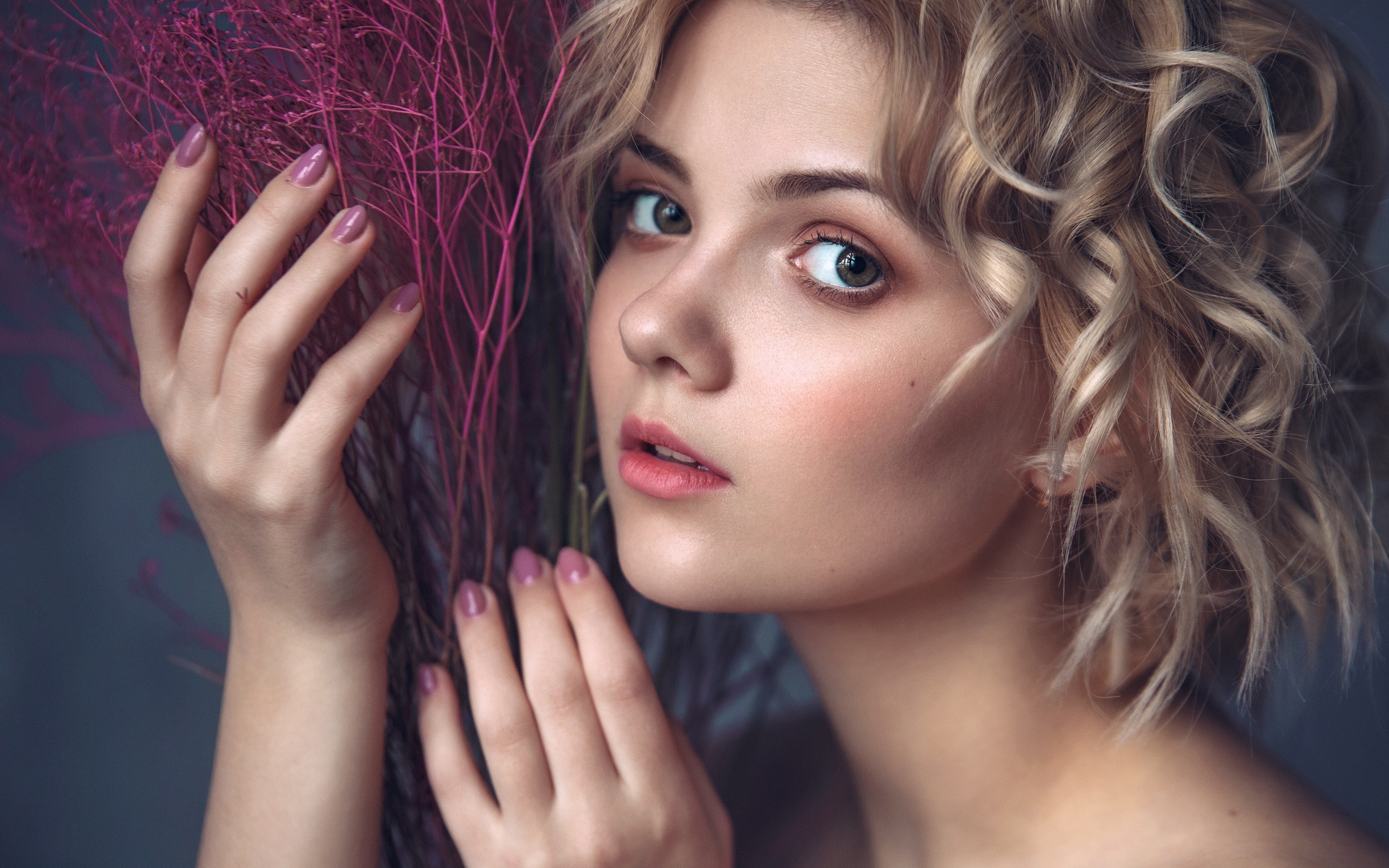 Красивая молодая блондинка с красным растением в руках