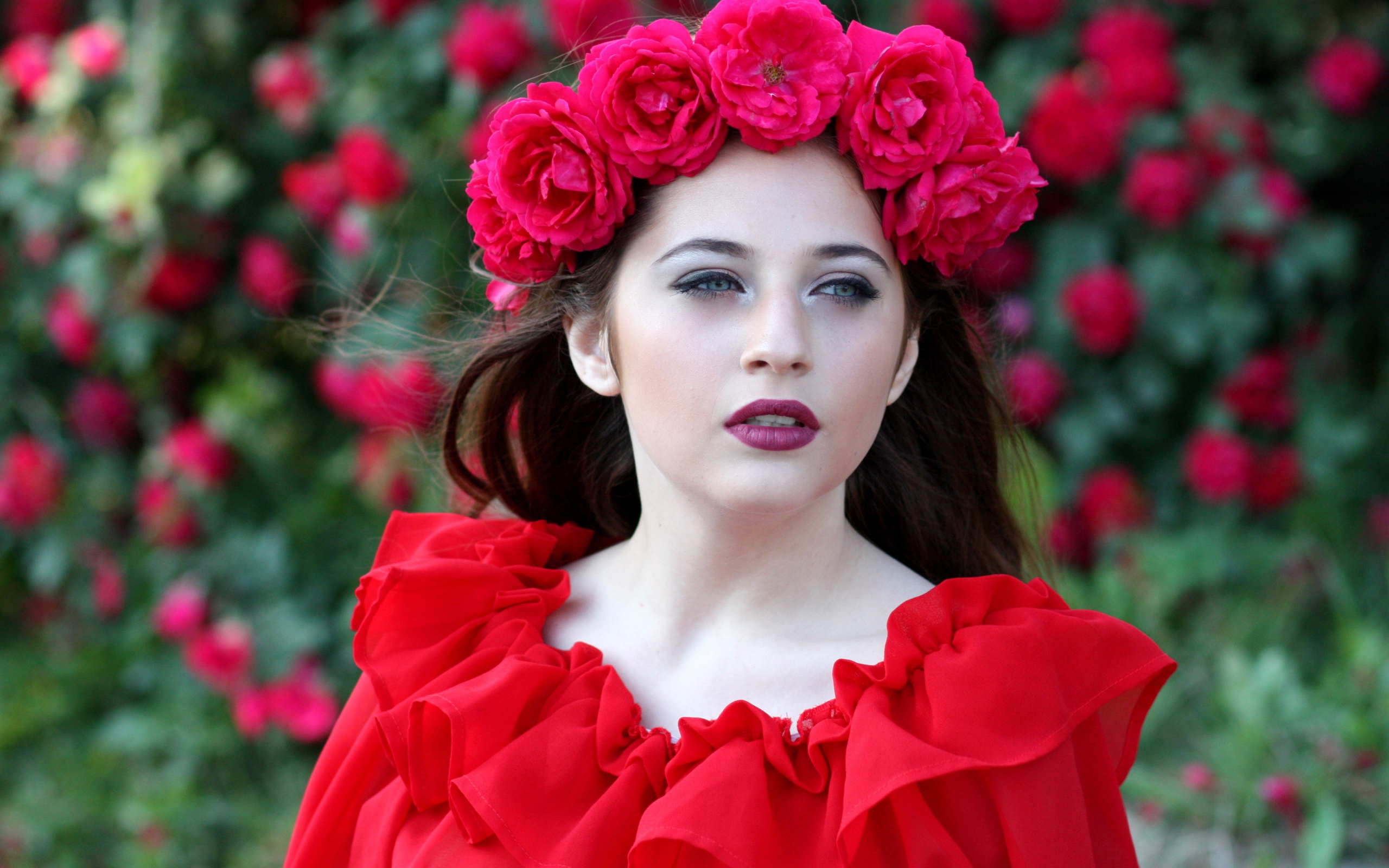 Яркая девушка в красном платье с венком из роз на голове